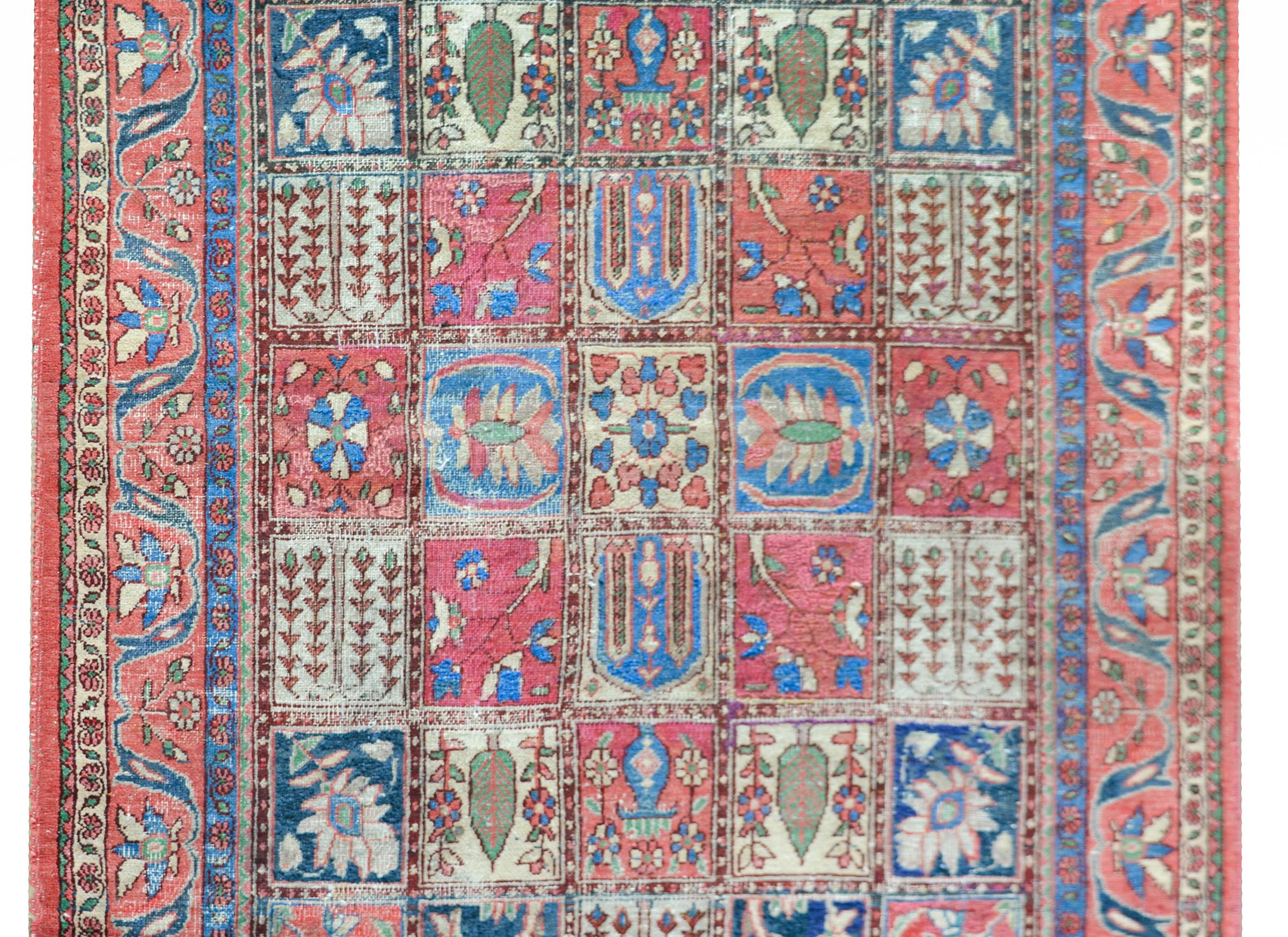 A wonderful mid-20th century Persian Bakhtiari rug with a patchwork pattern composed of a grid of varying floral patterns woven in crimson, indigo, green, and cream, and surrounded by a border with several floral and scrolling vine patterned stripes.