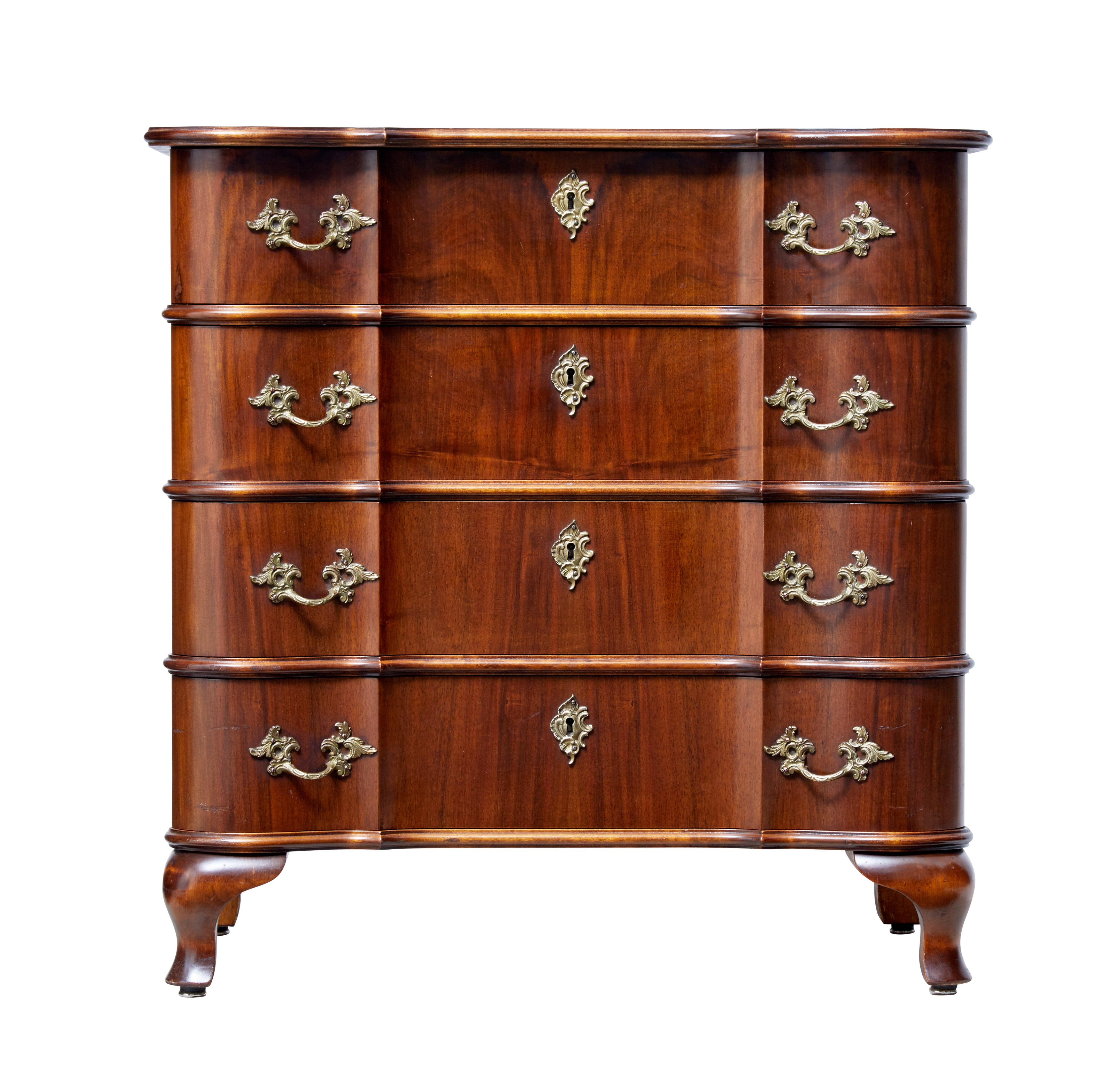 Elegant walnut commode of petit proportions, circa 1950.

Four-drawer chest with shaped drawer fronts and top. Fitted with ornate brass handles and escutheon plates.

Beautiful rich walnut color.

Minor surface marks to bottom drawer front.