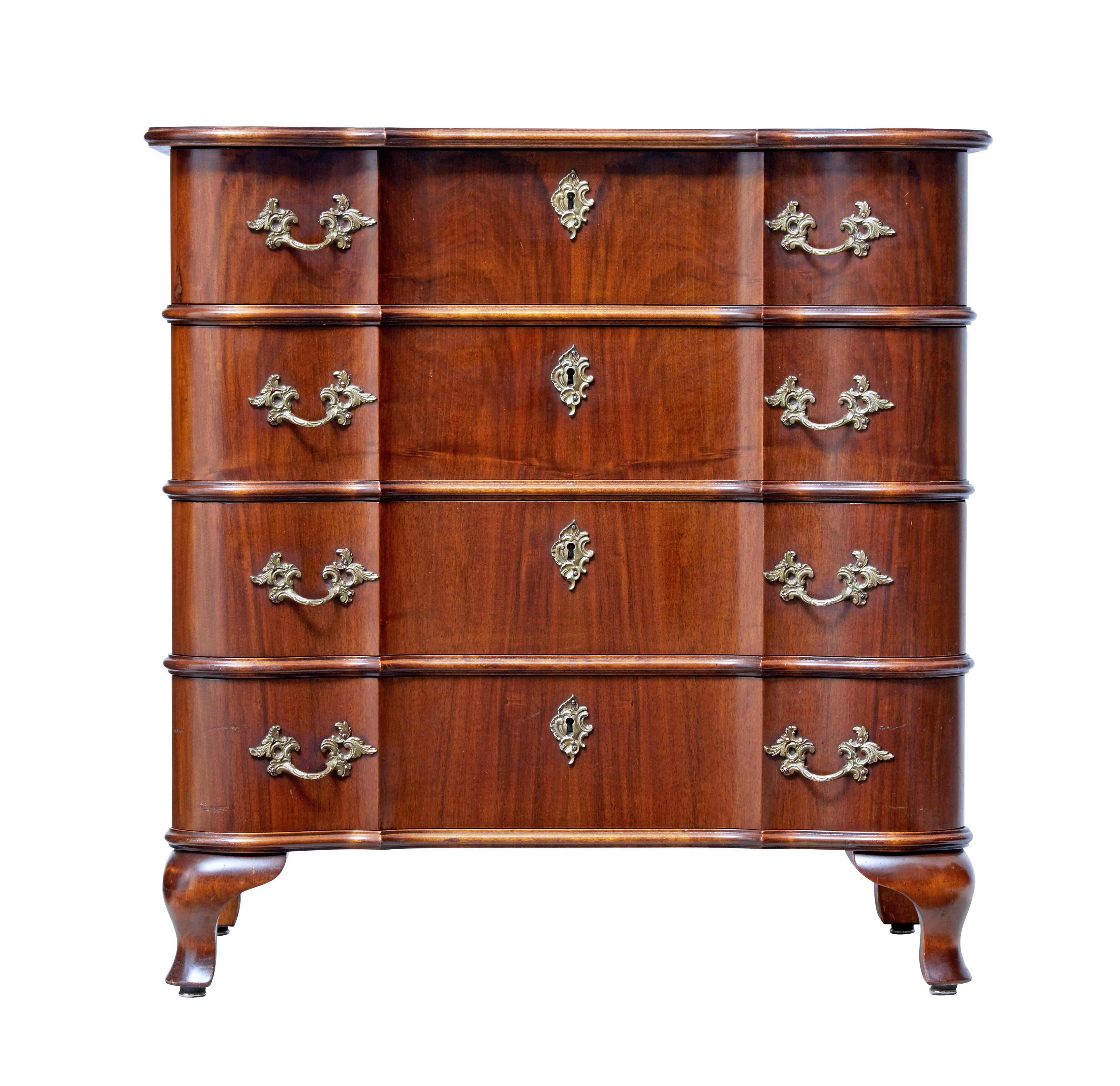 Mid-20th century baroque inspired walnut chest of drawers, circa 1950.

Elegant serpentine shaped walnut commode of petit proportions.

4 drawer chest with shaped drawer fronts and top. Fitted with ornate brass handles and escutheon