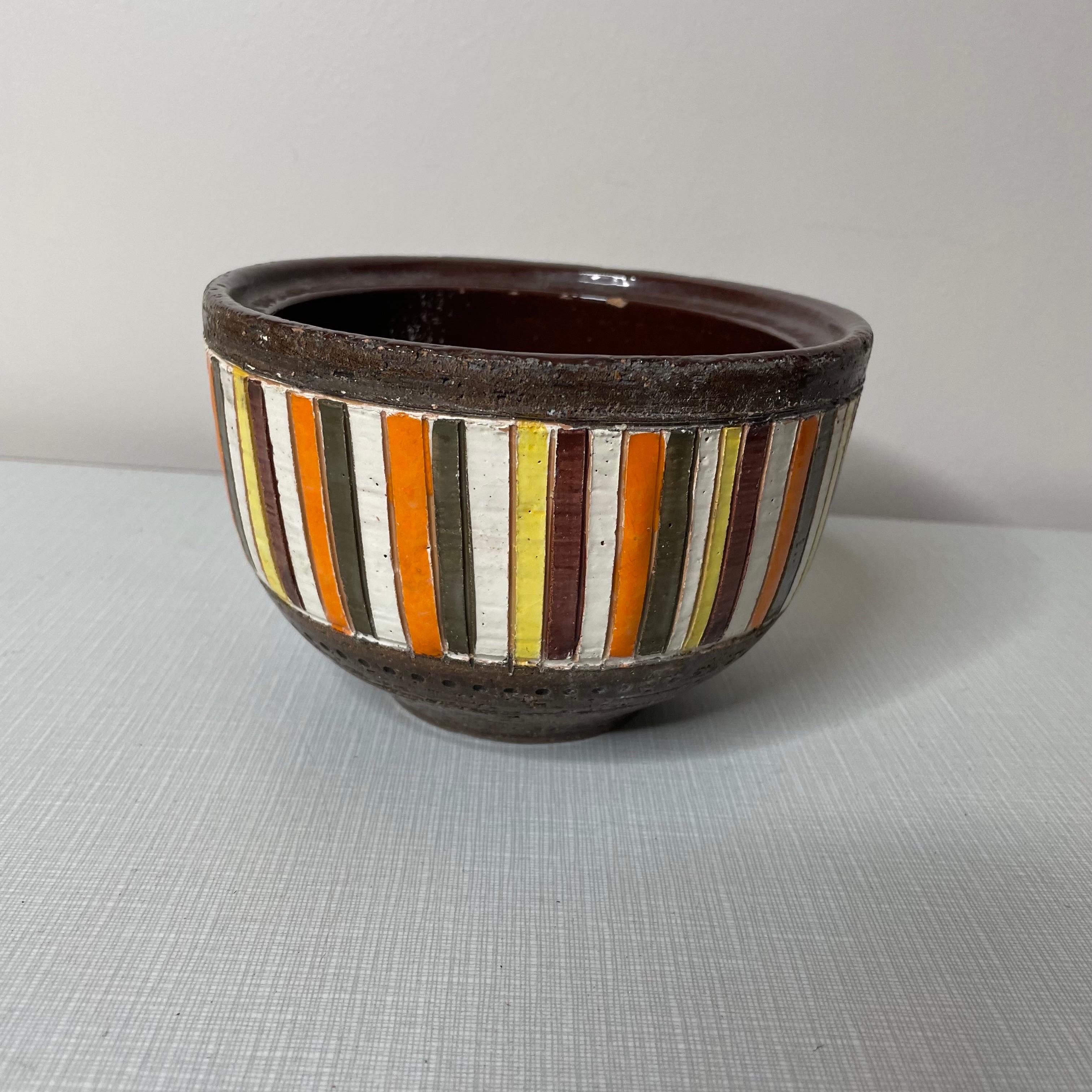 Italian-made bowl, or cachepot, or catchall. Made from ceramic with a band of brown glaze on the top and base. Vertical stripes in orange, yellow, white, and a sort of olive-brown color. Signed on the base, also retains the original Rosenthal-Netter