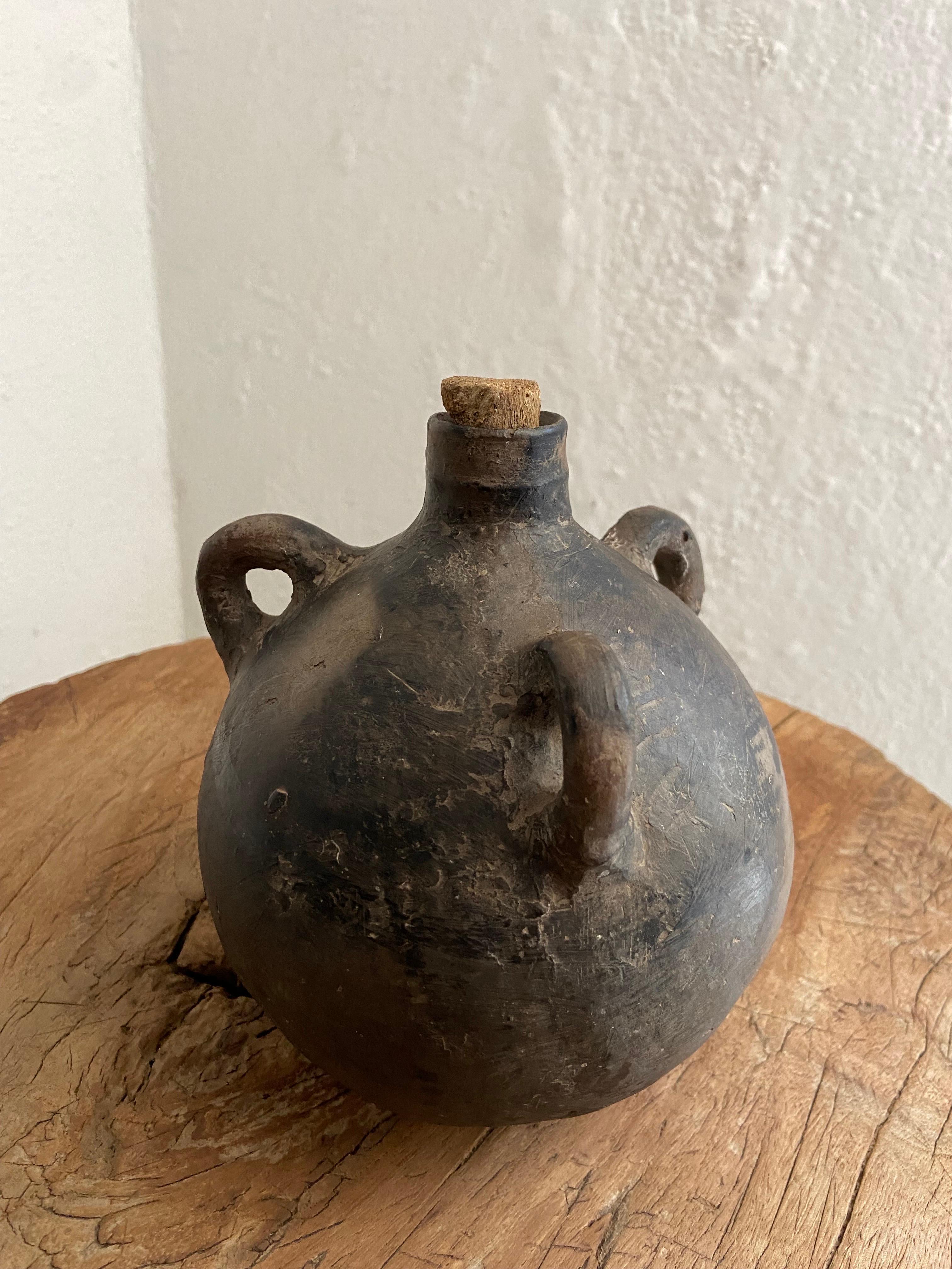 Mid 20th century black clay mezcal jug from Coyotepec, Oaxaca. The three handles are intact and used so the vessel can be carries using a thin gauge agave rope.