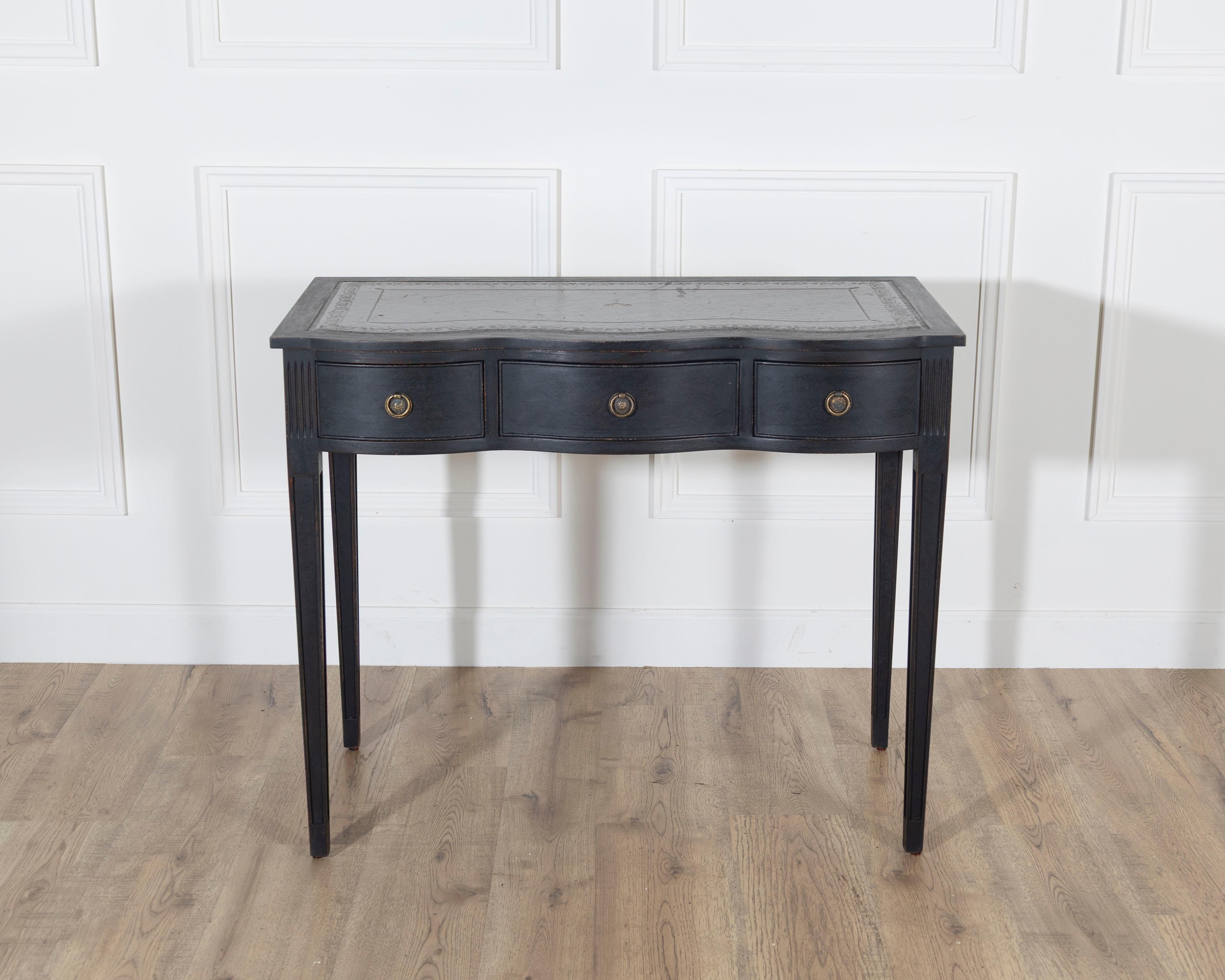 Elegant mid-20th-century console or writing desk featuring a graceful curved front and three spacious drawers fitted with brass ring pulls. The piece stands on slender, tapered legs that lend a refined and airy silhouette. The top retains its