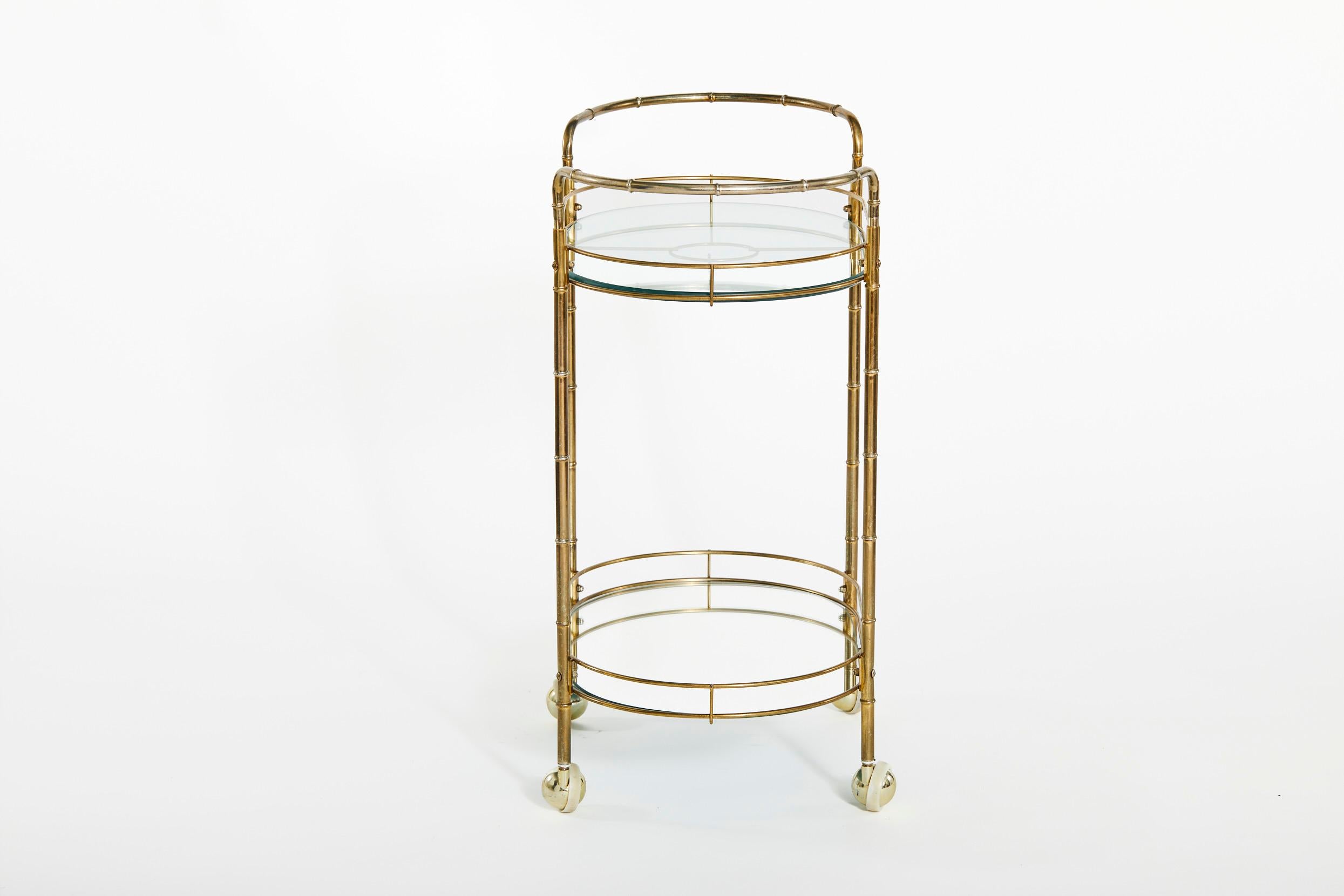 Beautiful mid 20th century brass frame with glass top two tiered wheeled bar cart. The bar cart features heavy glass shelve top, a lower mirrored shelve with side handle. The cart is in great condition. Minor wear consistent with age / use. The cart