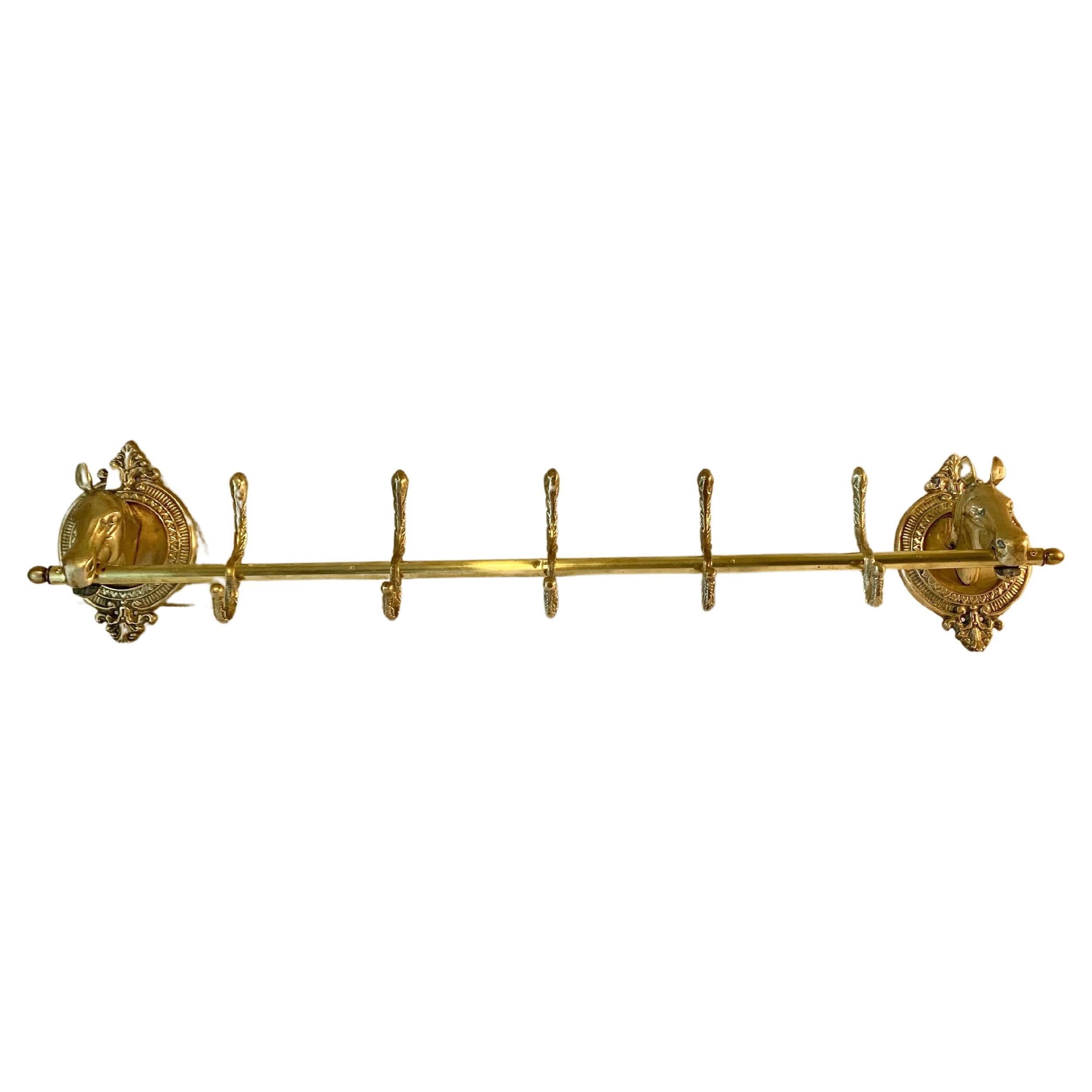 This large Mid 20th Century Horse Head Coat or Hat Rack was crafted from brass in the mid 1900's. The piece features two horse heads mounted on intricately detailed oval brass plaques that are adjoined by a center rod containing five hooks. Both the