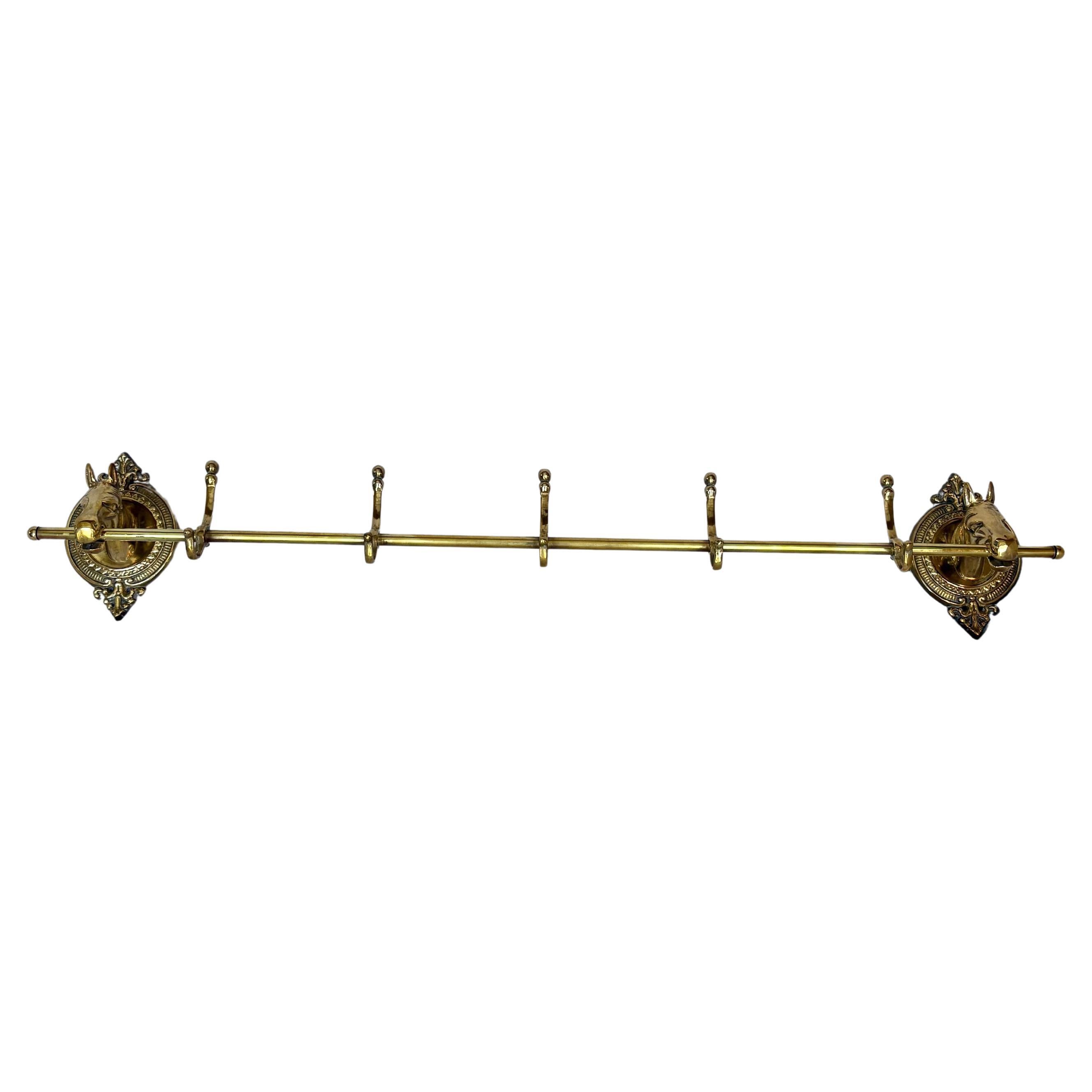 Questo grande appendiabiti a testa di cavallo della metà del XX secolo è stato realizzato in ottone a metà del 1900. Il pezzo presenta due teste di cavallo montate su placche ovali in ottone dai dettagli intricati, unite da un'asta centrale