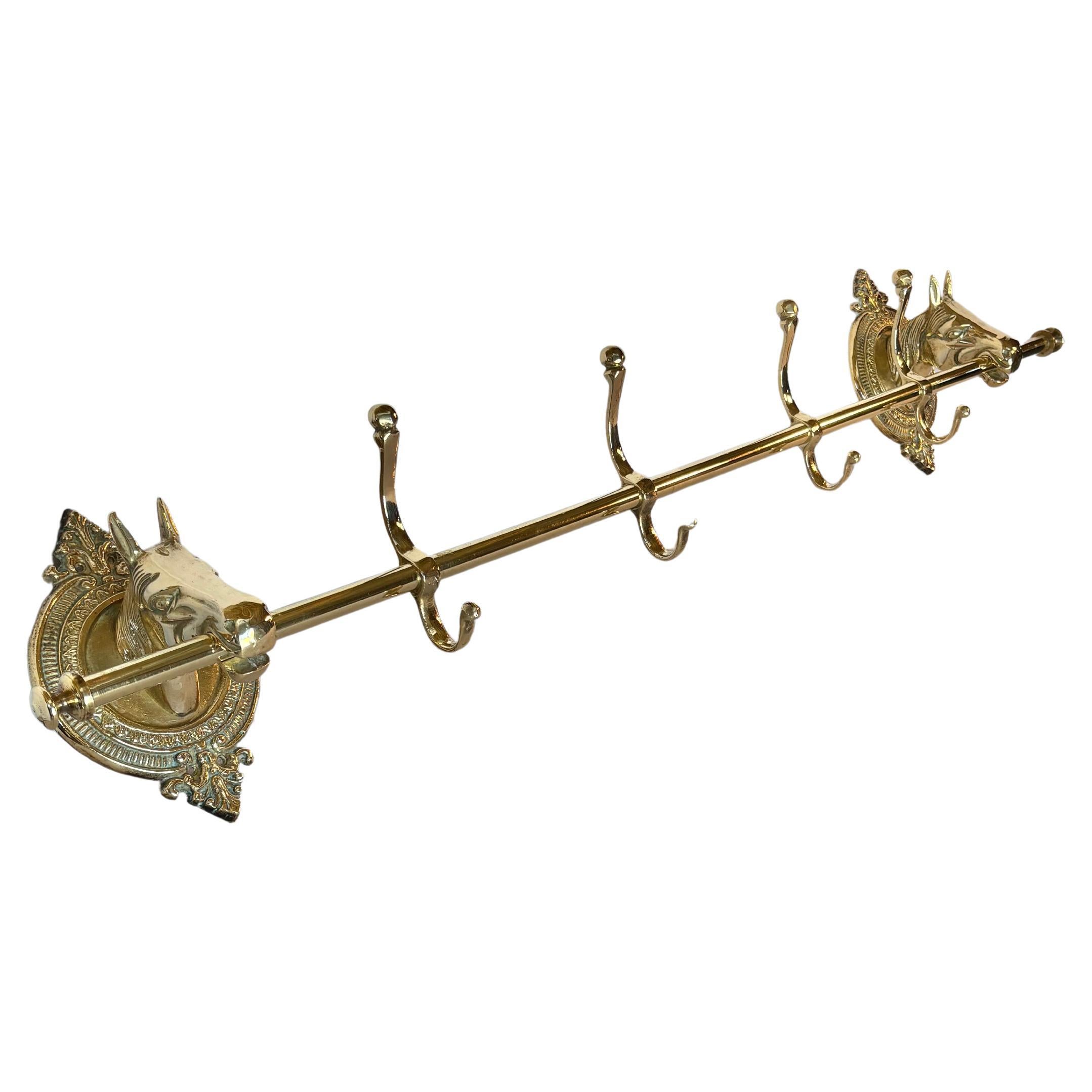 Questo grande appendiabiti a testa di cavallo della metà del XX secolo è stato realizzato in ottone a metà del 1900. Il pezzo presenta due teste di cavallo montate su placche ovali in ottone dai dettagli intricati, unite da un'asta centrale