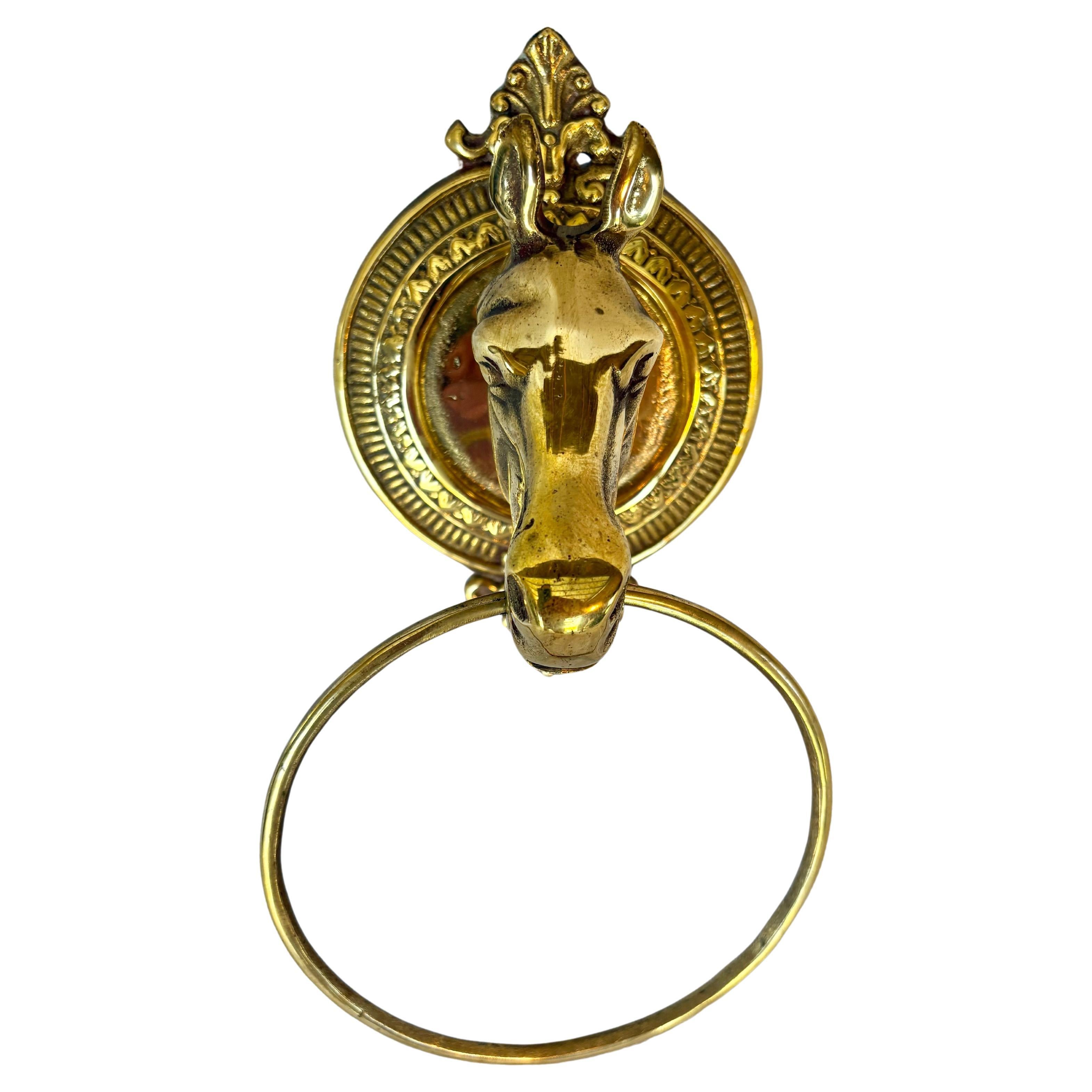 This Mid 20th Century Horse Head Towel Ring was crafted from brass in the mid 1900's. The piece features a horse head mounted on an intricately detailed oval brass plaque with a towel ring drop from the horses mouth. The brass shows great aged