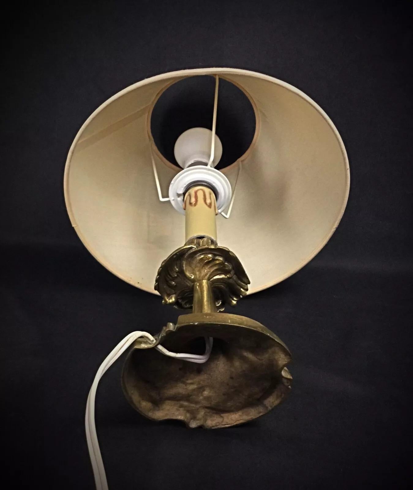 Questa base per lampada in ottone vintage della metà del XX secolo presenta un design classico ed elegante, perfetto per aggiungere un tocco senza tempo a qualsiasi spazio. La lampada è dotata del suo paralume originale, il che la rende un
