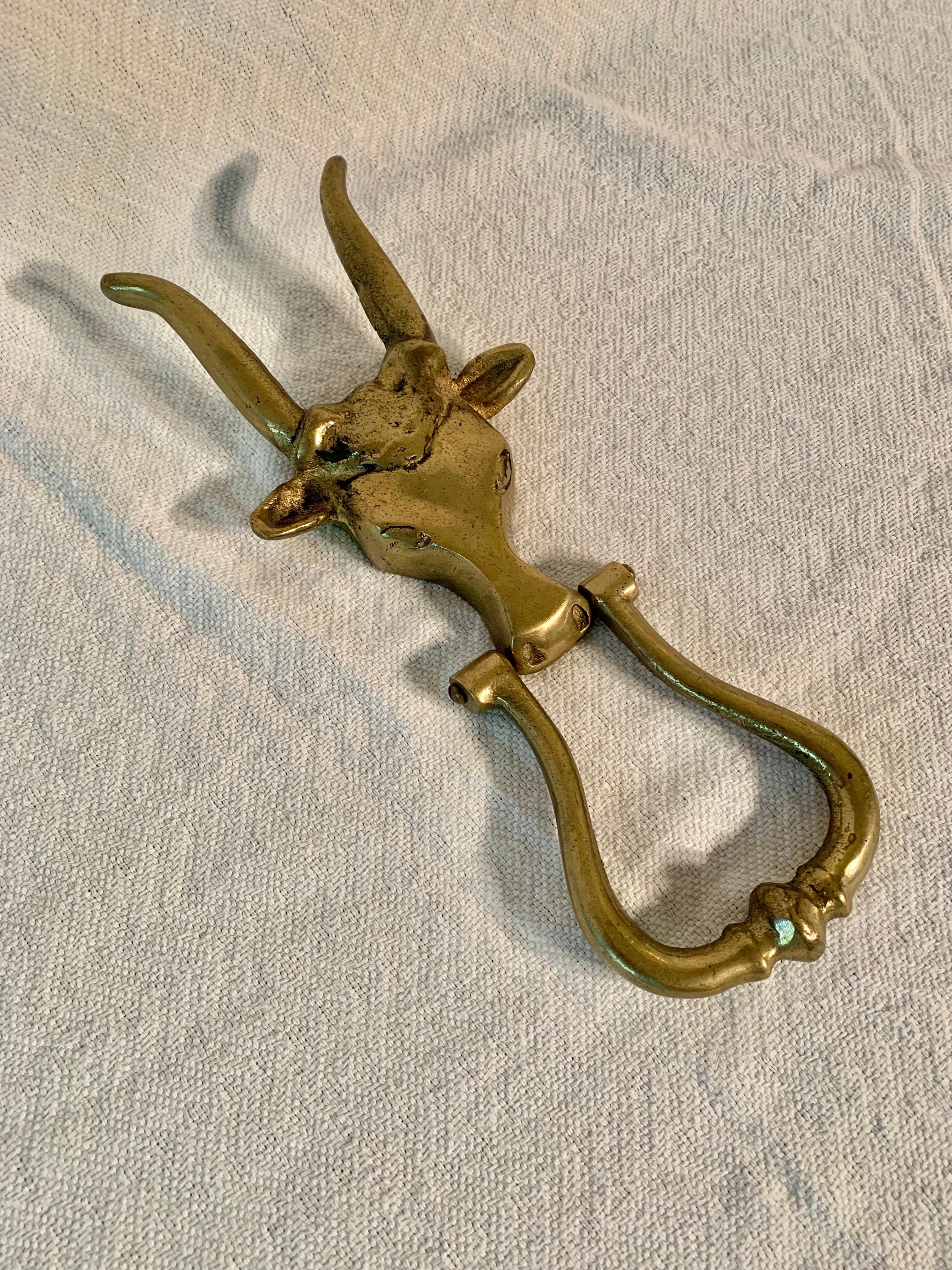 Questo battente in ottone con mucca o toro Longhorn della metà del XX secolo è stato realizzato da artigiani nella metà del 1900. Il battiporta è caratterizzato da una testa di mucca o di toro longhorn con un volto intricato e dettagliato. Il pezzo