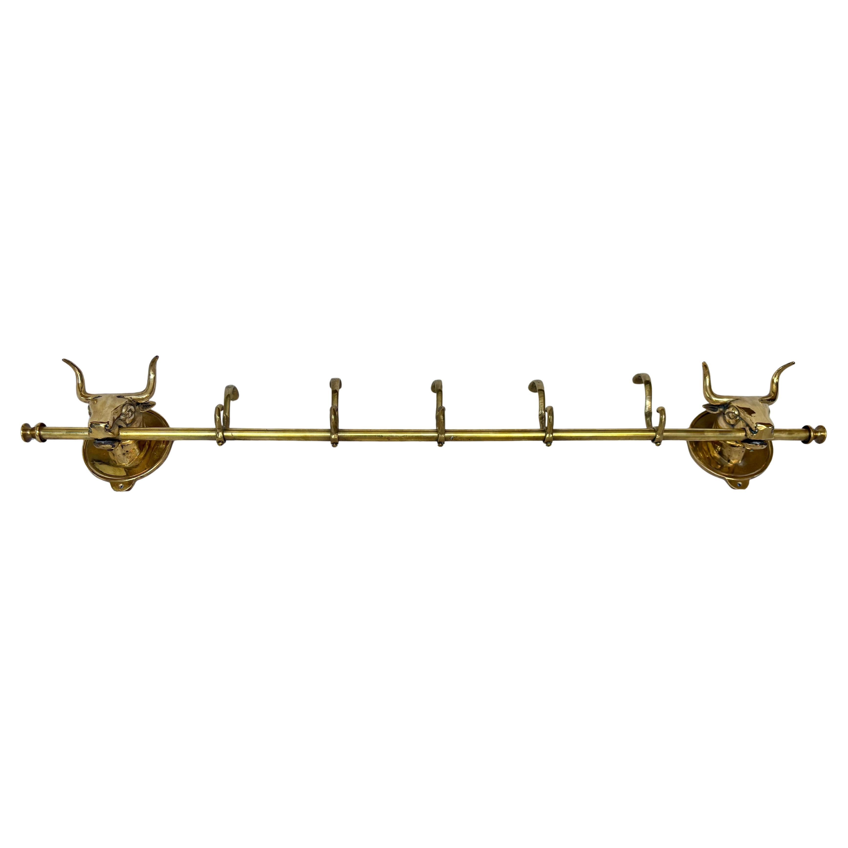 Questo grande appendiabiti a testa di mucca longhorn della metà del XX secolo è stato realizzato in ottone a metà del 1900. Il pezzo presenta due teste di mucca montate su placche ovali in ottone che sono adiacenti a un'asta centrale contenente