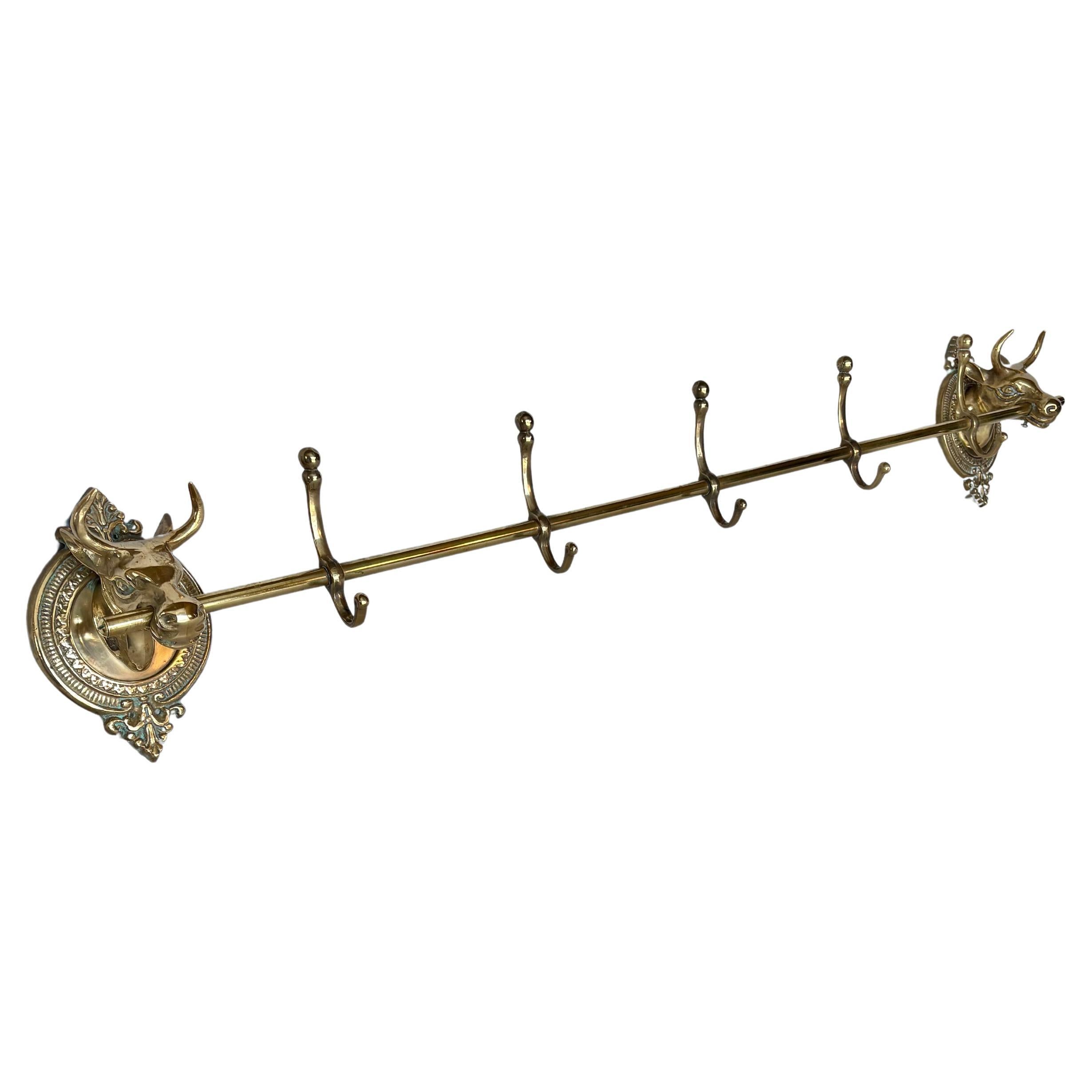 This large Mid 20th Century Longhorn Cow Head Coat or Hat Rack was crafted from brass in the mid 1900's. The piece features two cow heads mounted on intricately detailed oval brass plaques that are adjoined by a center rod containing five hooks.