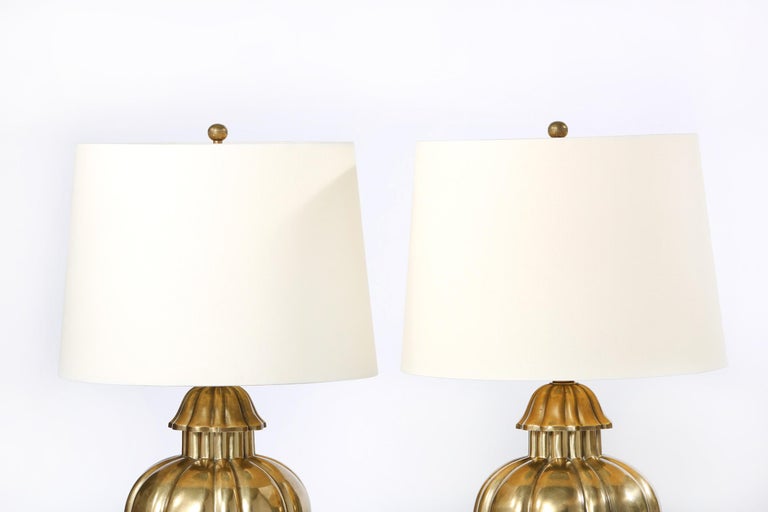 North American pair of solid brass table lamps with wood base. Each lamp is in excellent vintage working condition. Minor wear consistent with age / use. Each comes with an oval drum shade size 11.5