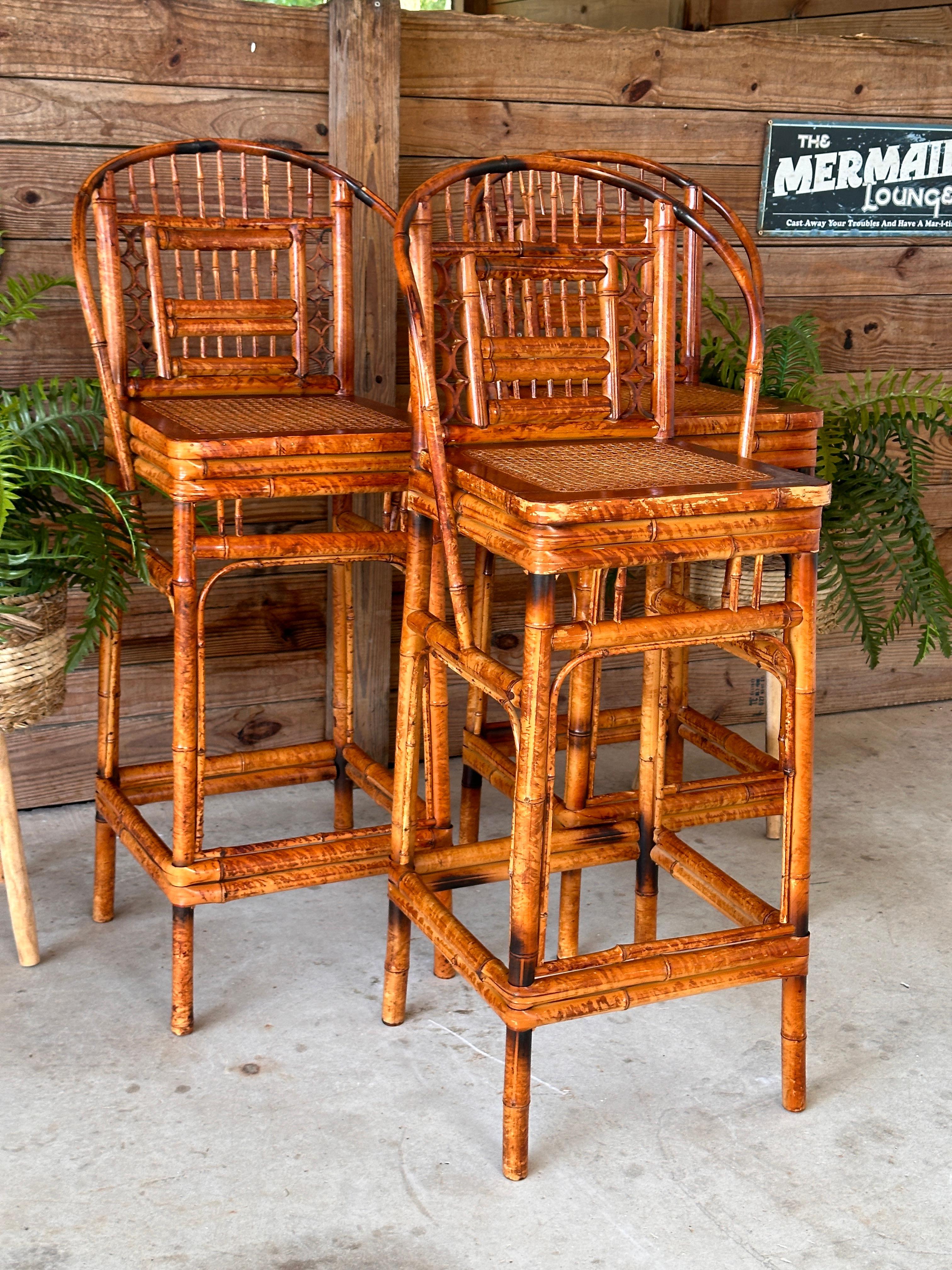 Set of three stunning Mid-20th Century Bamboo and Cane Bar Stools, designed in the manner of Brighton Pavilion.
Featuring elegantly curved bamboo frames, intricate fretwork backs, and cane seats, these stools embody the charm of vintage