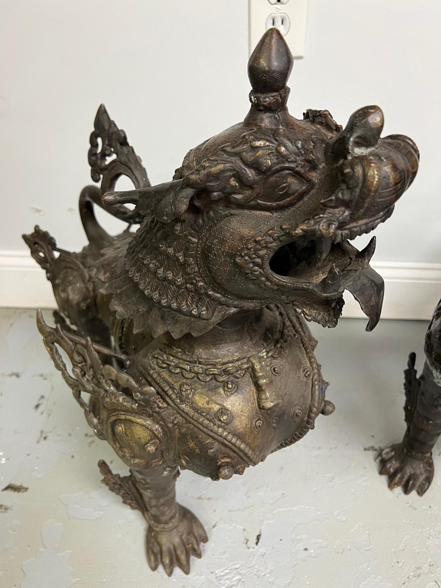 Impressive pair of large bronze Foo Dogs or Tibetan snow lions in full armor. Tibetan snow lions are known for protective qualities, they are celestial animal emblem of Tibet that embodies power, playfulness, fearlessness and joy. The snow lion is