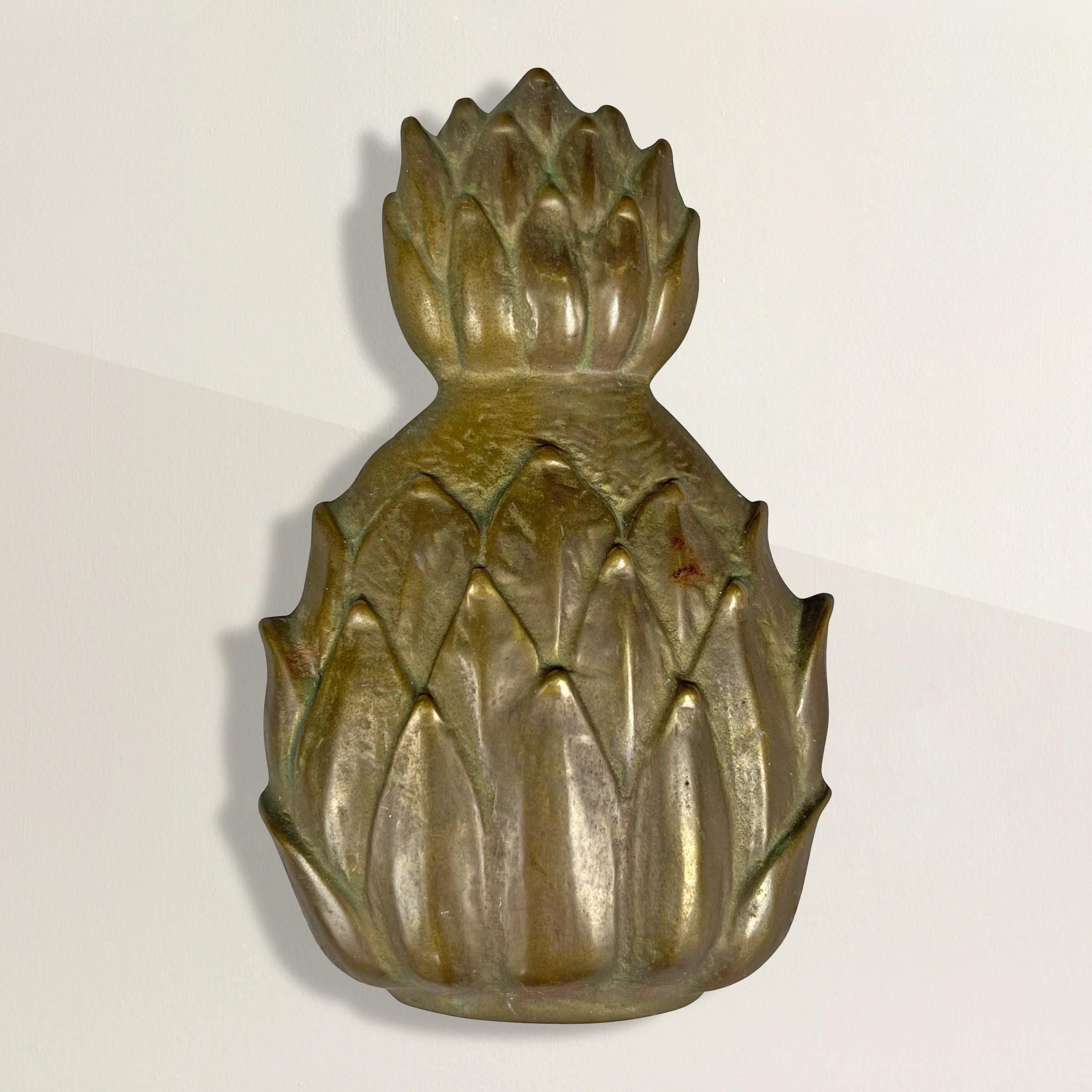 Rehaussez l'entrée de votre maison avec ce remarquable heurtoir américain en laiton moulé du milieu du XXe siècle, méticuleusement façonné en forme d'ananas. Au-delà de son esthétique étonnante, l'ananas recèle un symbolisme profond qui ajoute une