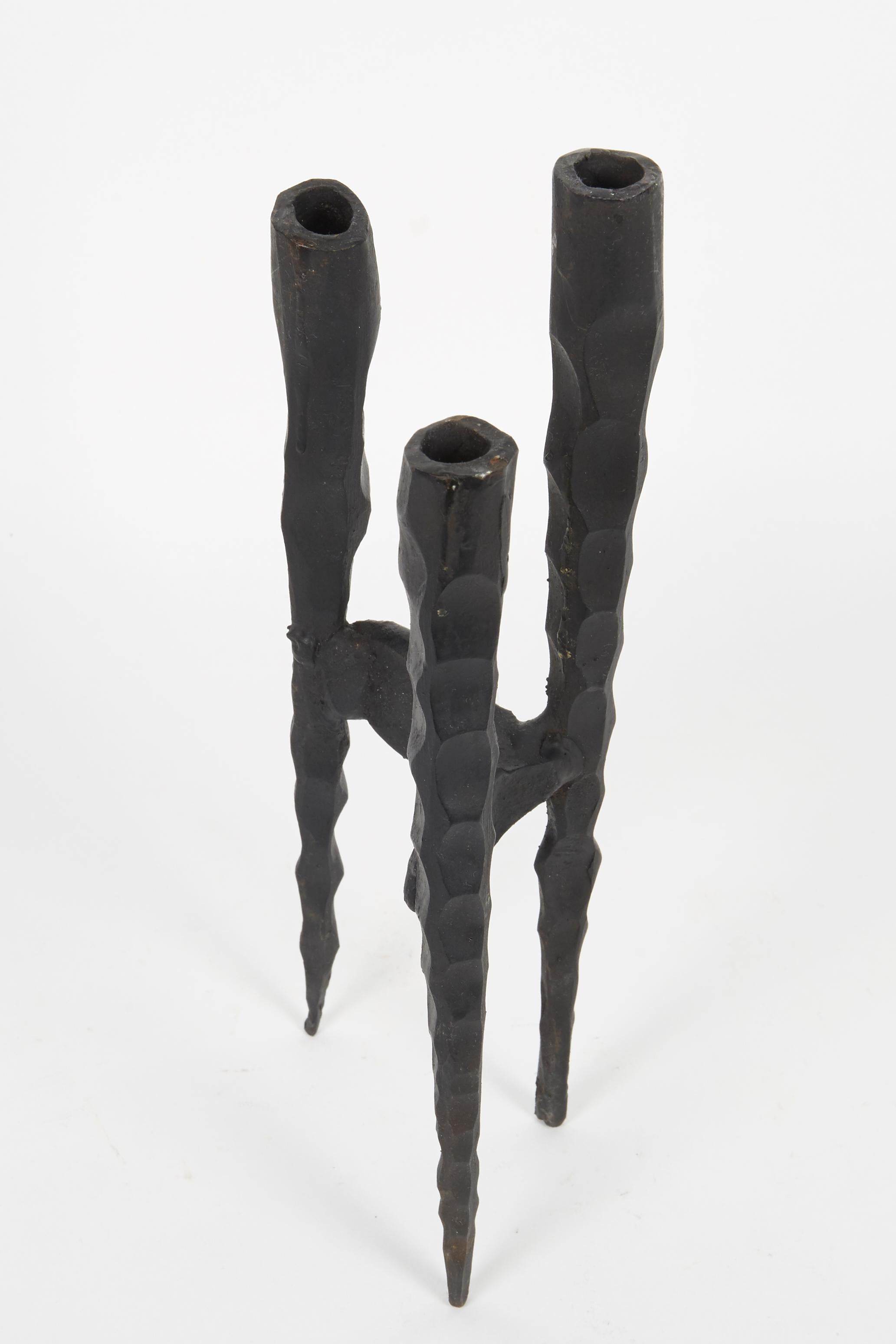 Kleiner Shabbat-Kerzenhalter aus Eisen im brutalistischen Stil von David Palombo. Die für drei Kerzen ausgelegten Halter laufen in der Mitte zusammen und bilden so eine zusammenhängende, konische Form. 

David Palombo (1920-1966) war ein in der