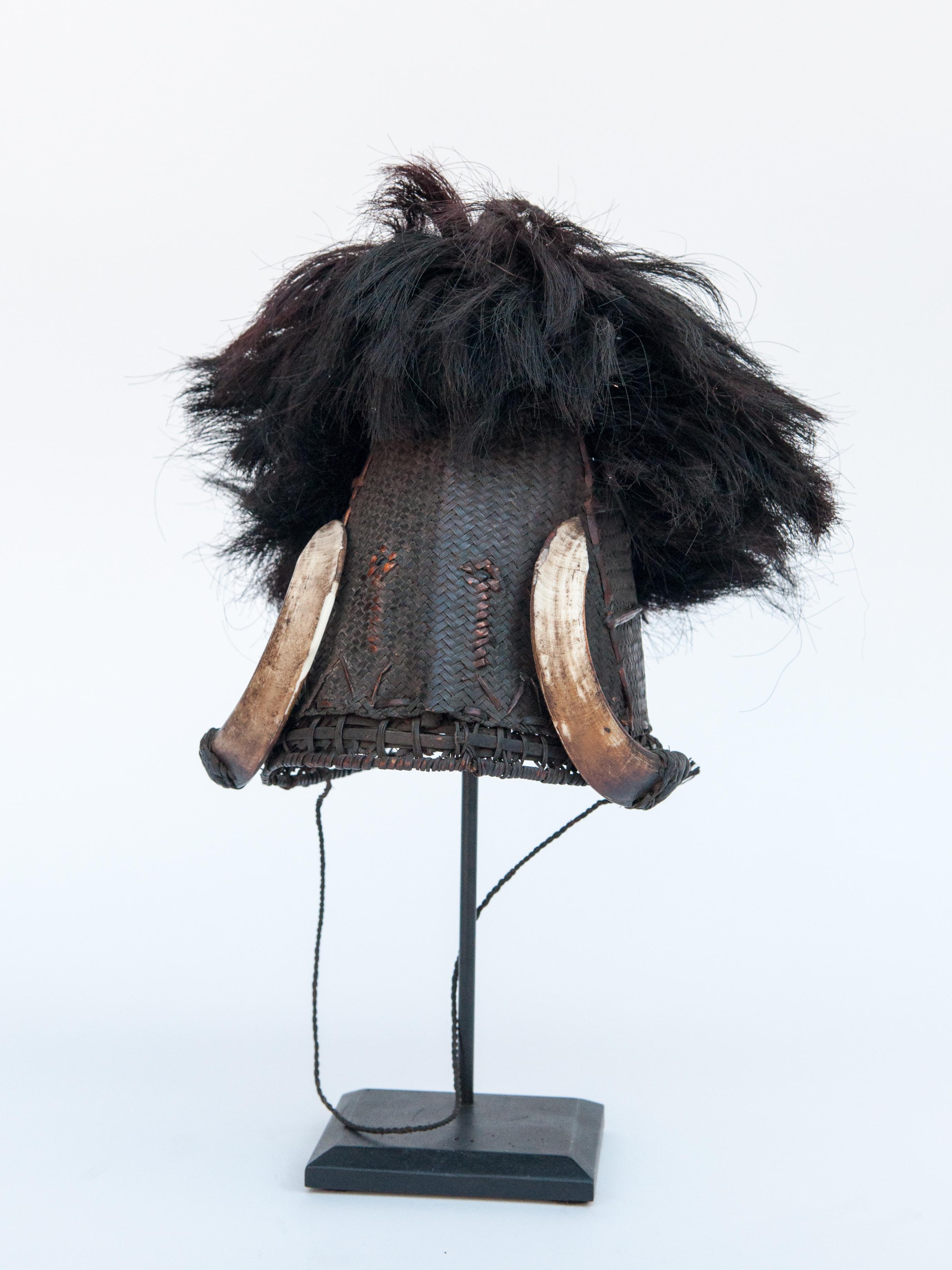 Mid-20th century cane warriors hat boar tusk and goat hair, Konyak, Naga, NE India. Mounted on a metal stand.
This is a ceremonial warriors hat from Nagaland, attributed to the Konyak Naga, but it may have come from any of a diverse collection of