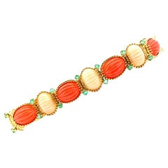 Gliederarmband aus 18 Karat Gelbgold mit geschnitzter Koralle und Smaragd, Mitte des 20. Jahrhunderts