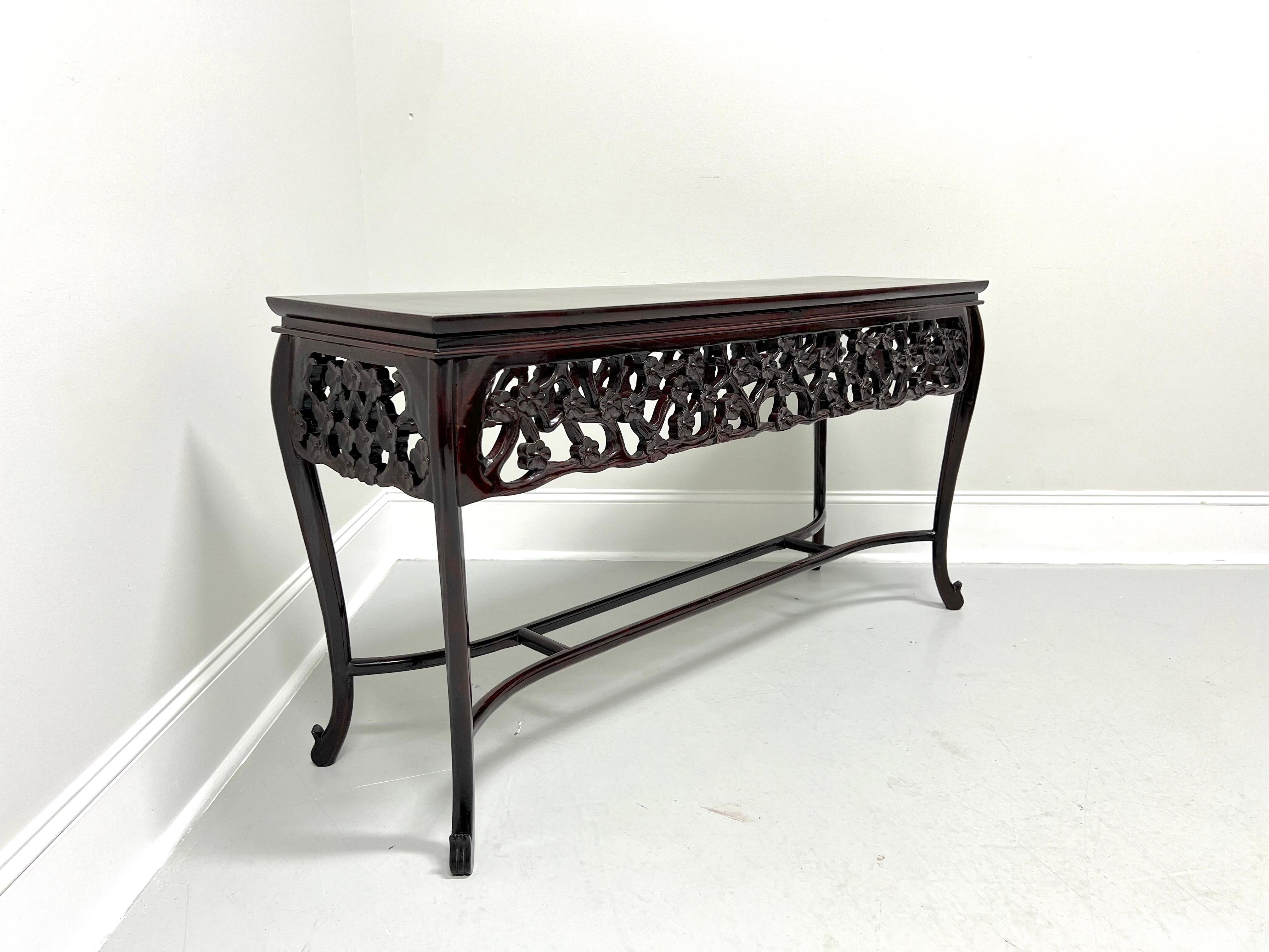 An Asian style console sofa table, unbranded. Unknown wood type with a rosewood finish, banded top with miter edge, decoratively carved floral & branches apron, curved legs, stretchers forming an undertier, and modified paw feet. Likely made in