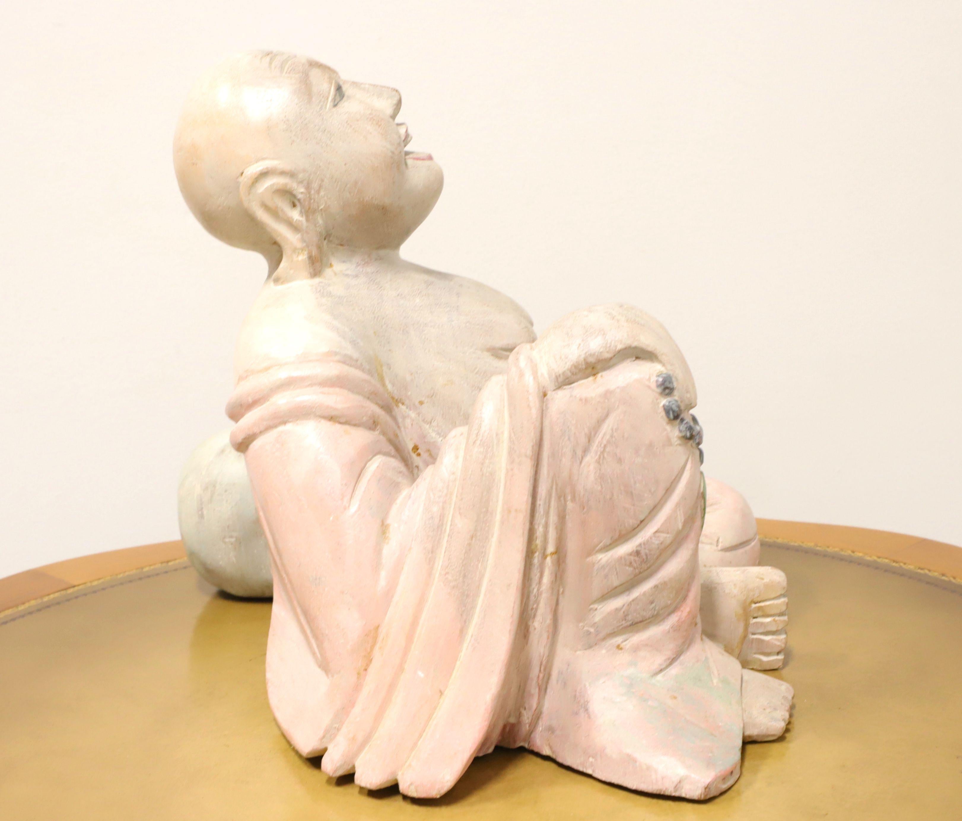 Sculpture en bois représentant un bouddha assis et souriant. Non signé, artiste inconnu. Sculptée dans une pièce de bois massif et peinte dans des tons chair, rose et vert. Origine inconnue, probablement l'Asie, et produit au milieu du 20e siècle.