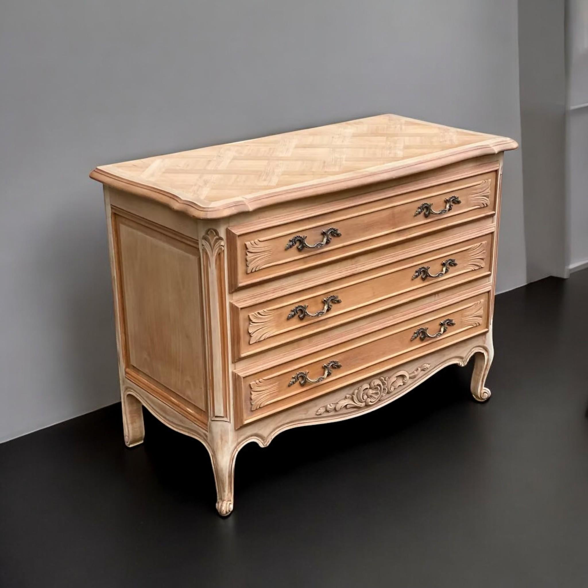 This elegant three-drawer commode is designed in the Louis XV style, capturing the flowing lines and refined ornamentation characteristic of 18th-century French Rococo. Crafted in the mid-20th century, the piece features a beautifully sculpted