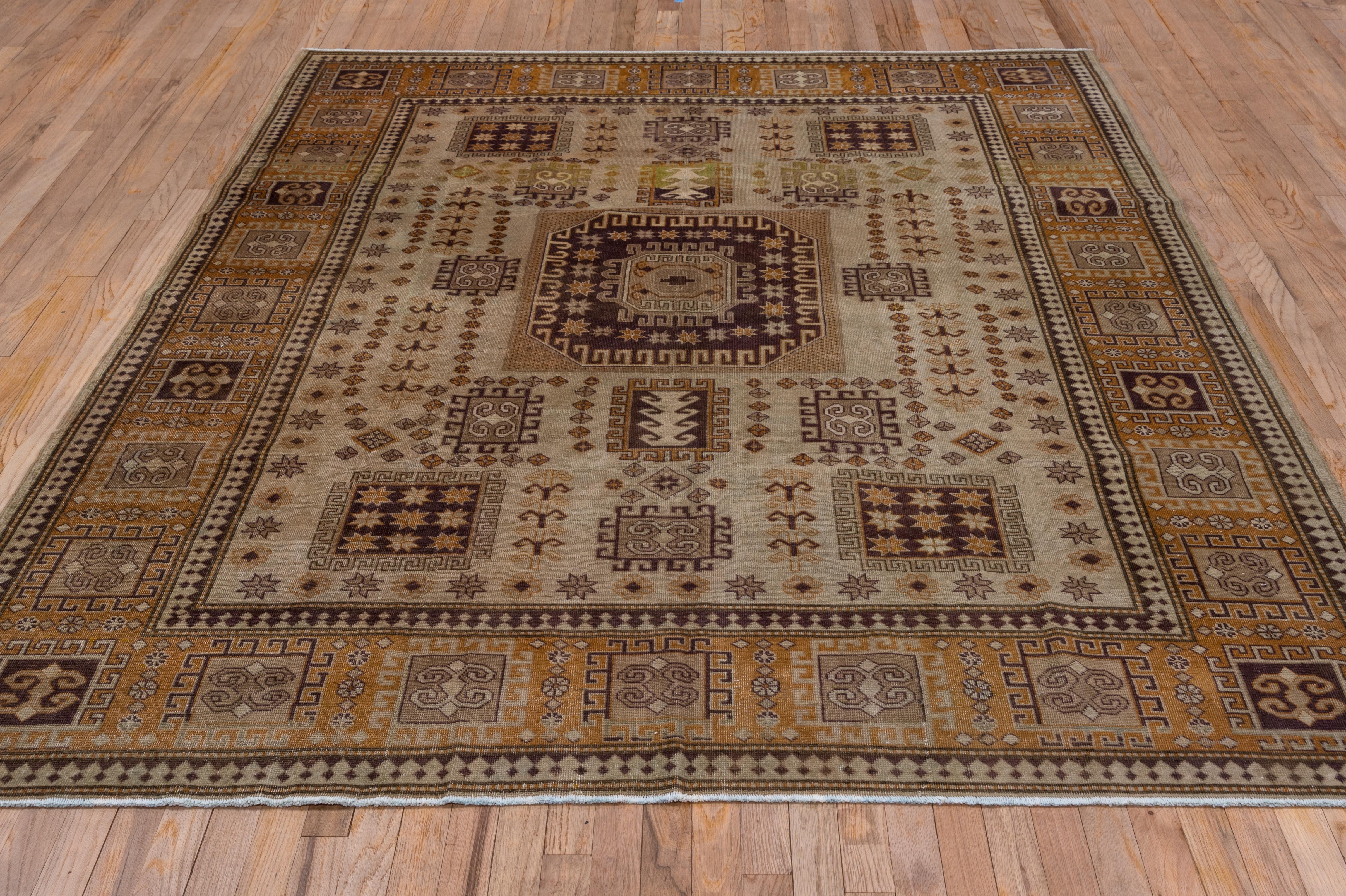 In the Caucasian Karachof Kazak style, this southern European carpet shows internally starred and hooked brick octagonal medallion on a sand field with characteristic star-filled boxes and other hooked quadrilaterals. The ochre border shows more