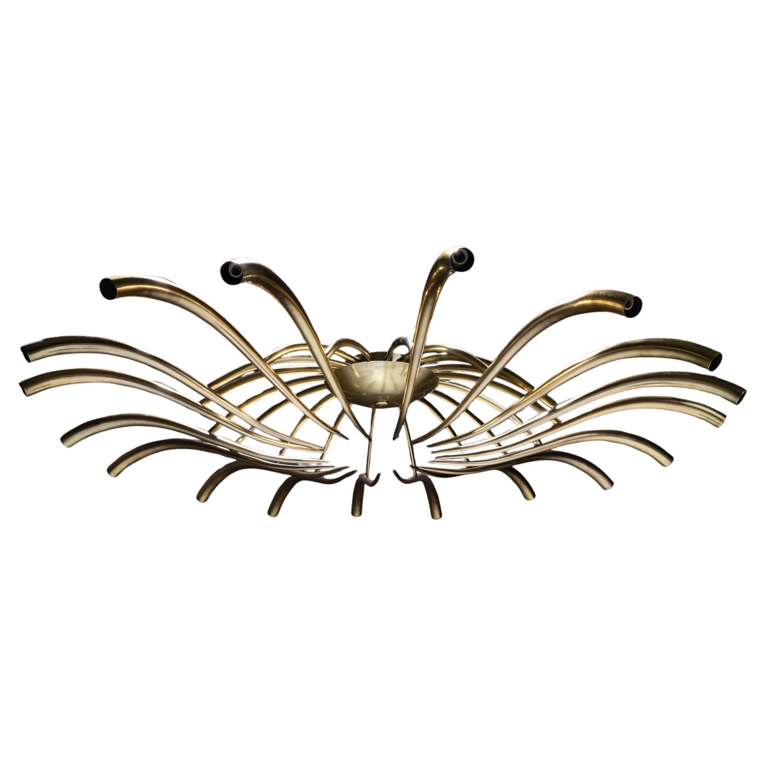 Large and rare chandelier designed by Oscar Torlasco for Lumi, circa 1955. Crafted from polished brass, the fixture features 18 elegantly curved arms radiating outward from a central brass ring adorned with fine, thin rods. A sculptural and striking