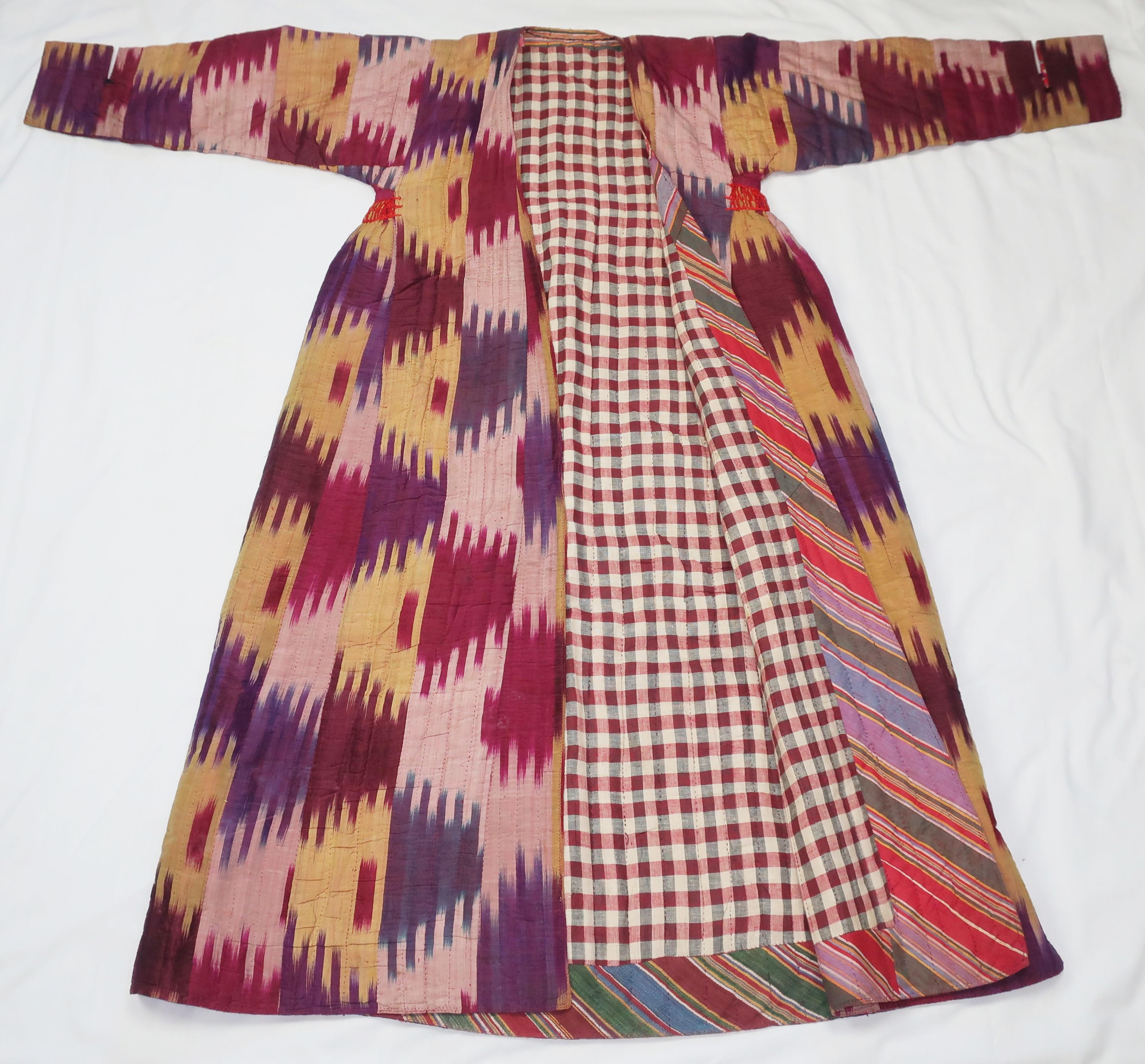A beautiful early to mid 20th Century quilted silk woman's robe from the Mazar-i-Sharif region of Northern Afghanistan, Central Asia.  The robe is in a traditional Ikat pattern displaying shades of purple, aubergine, magenta, peacock blue, pale