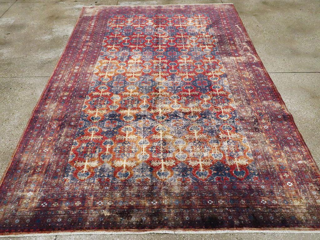 Ce tapis en soie finement tissé présente un champ rouille avec un motif répétitif d'octagrammes bleus faisant jaillir des paires de fleurs semblables à des œillets dans la direction verticale, avec des paires de fleurs similaires en forme d'haltères