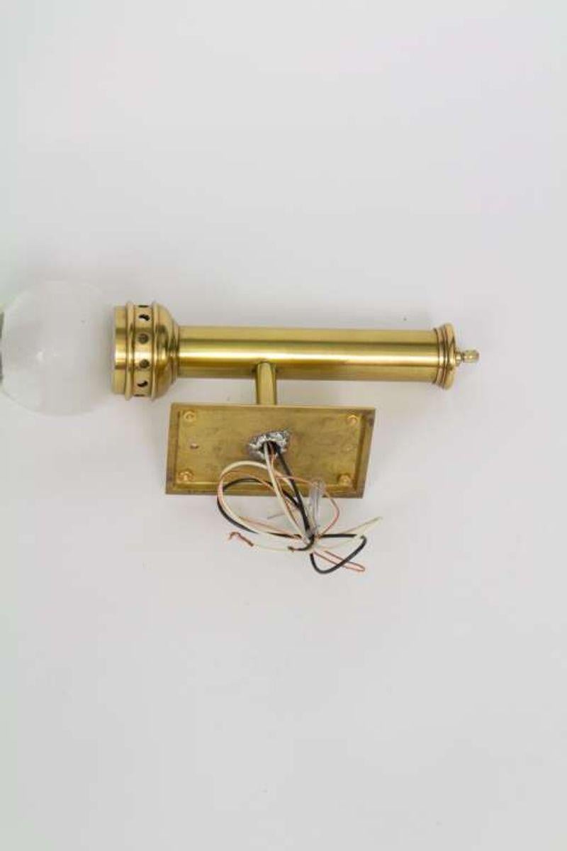 Iconic Chapman railway lantern sconces. Brass with glass globes. Excellent condition. Polished and lacquered, rewired with new sockets. Designed to be mounted directly onto wood panels, may need a custom plate for other wall types. Made in Hong