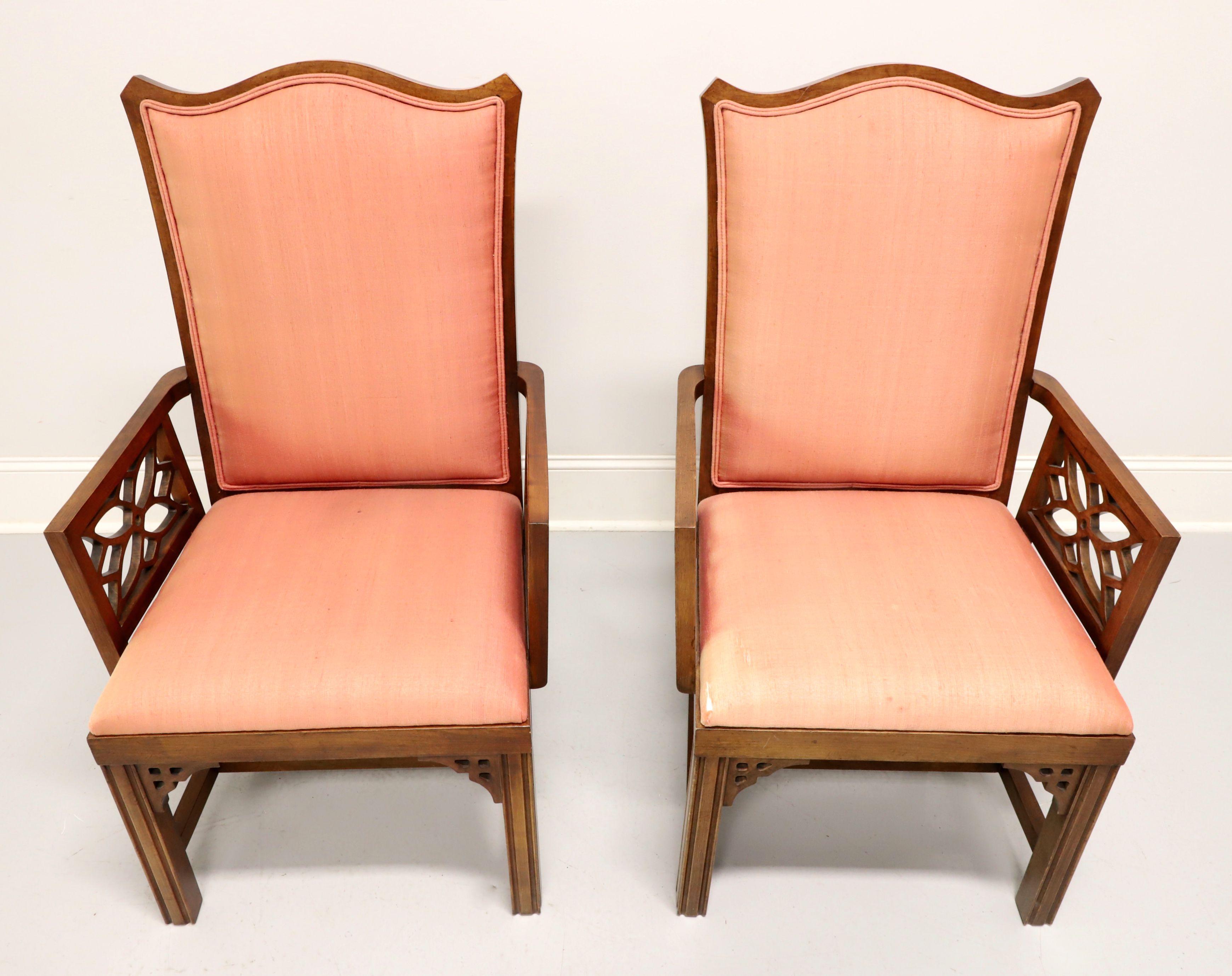 A pair of Asian inspired dining armchairs, unbranded, likely Thomasville or American of Martinsville. Cherry with decorative fretwork accents under apron at corners, carved design to chair back, squared arms with carved design, salmon color fabric