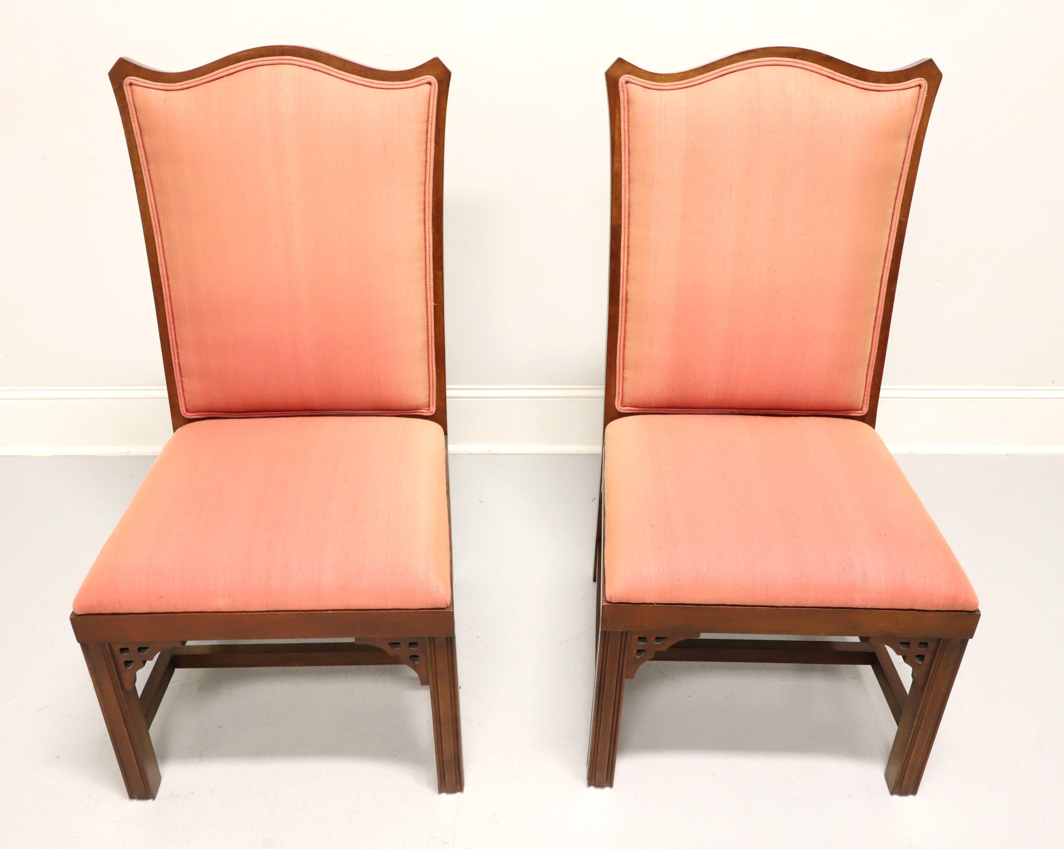A pair of Asian inspired dining side chairs, unbranded, likely Thomasville or American of Martinsville. Cherry with decorative fretwork accents under apron at corners, carved design to chair back, salmon color fabric upholstered backrest & seat,