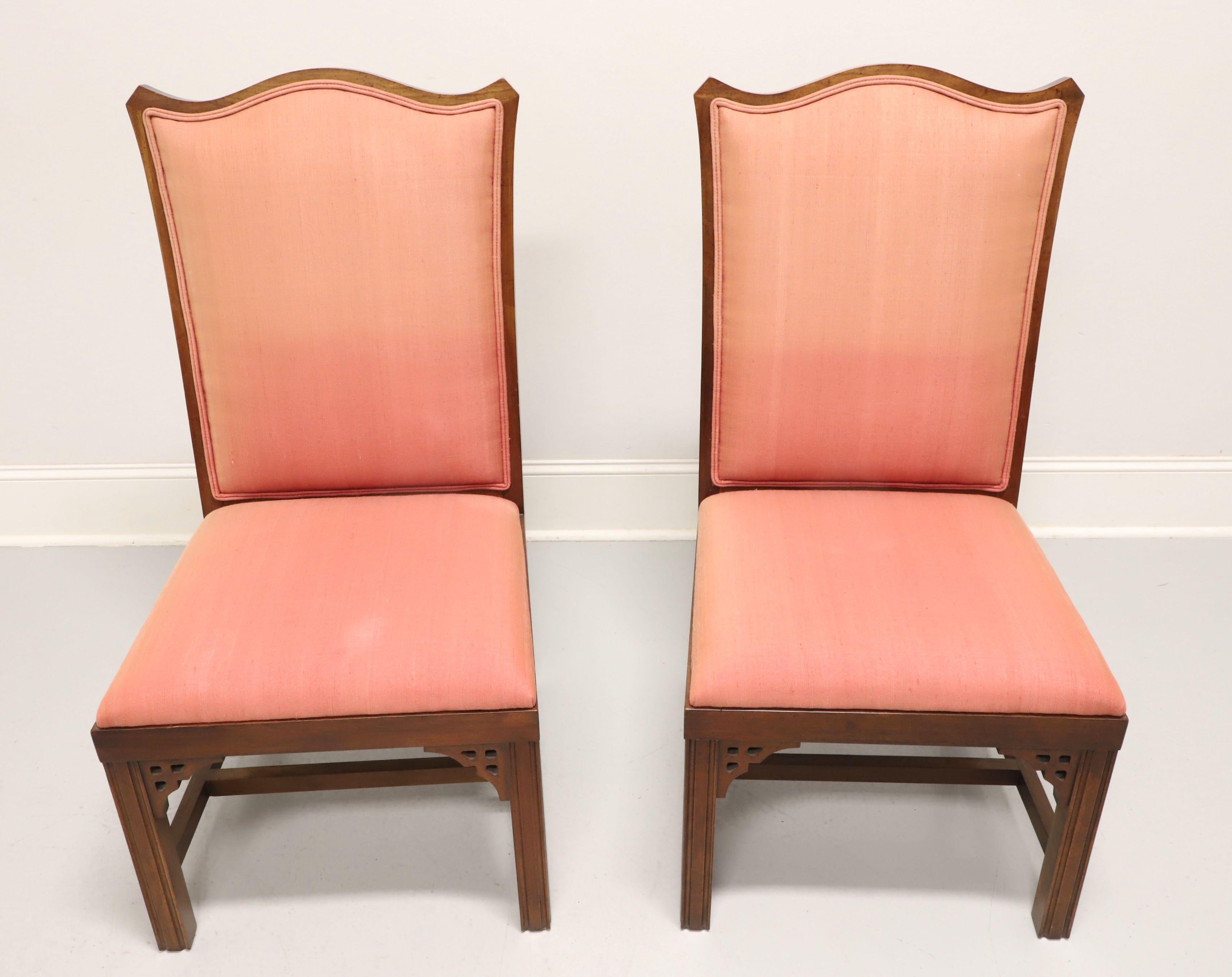 A pair of Asian inspired dining side chairs, unbranded, likely Thomasville or American of Martinsville. Cherry with decorative fretwork accents under apron at corners, carved design to chair back, salmon color fabric upholstered backrest & seat,