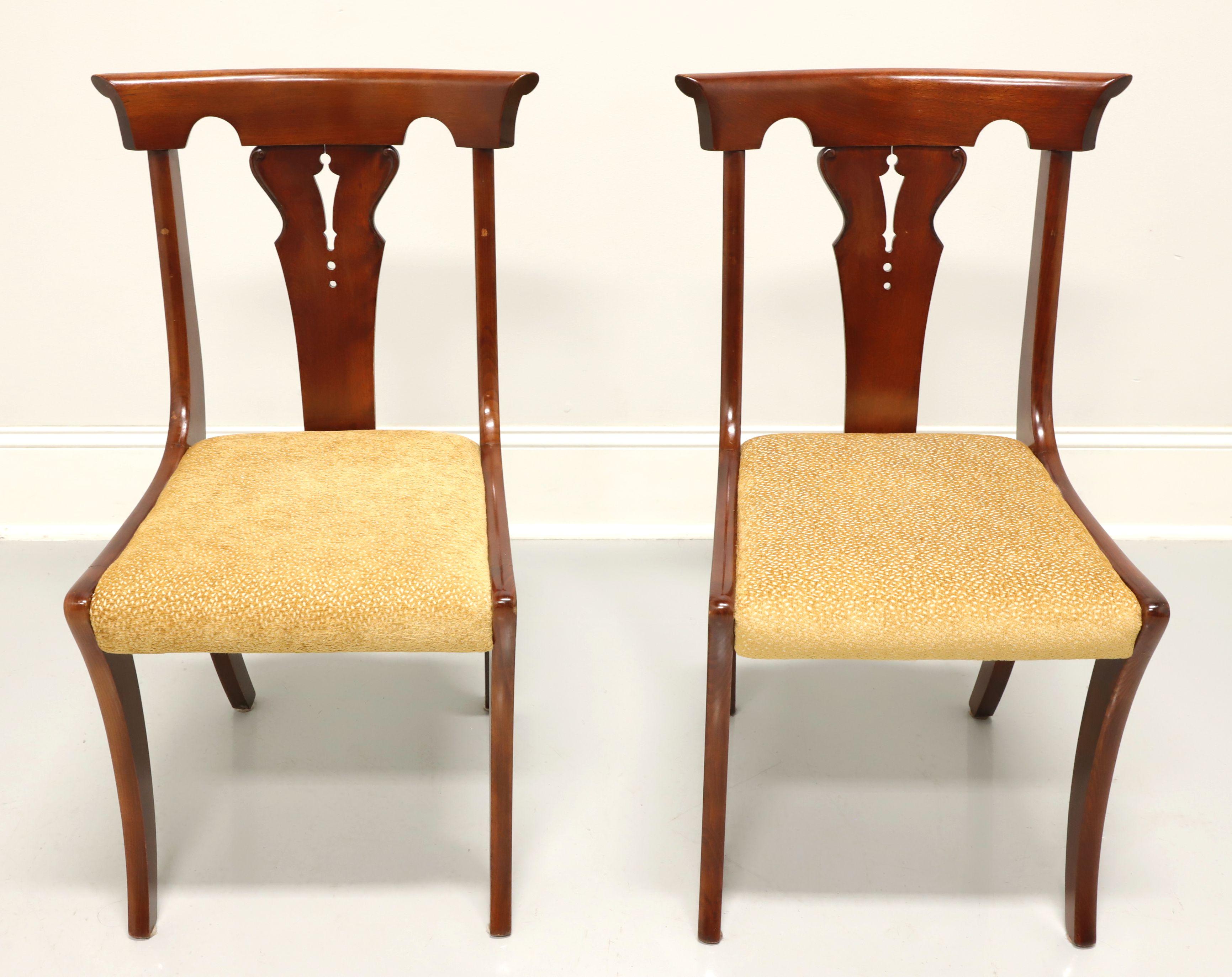 A pair of dining side chairs in the Empire style, unbranded. Solid cherry with carved barback crest rail, carved backrest, upholstered seat in a gold colored textured fabric and gently curved legs with rear stretcher.  Made in USA, in the mid 20th