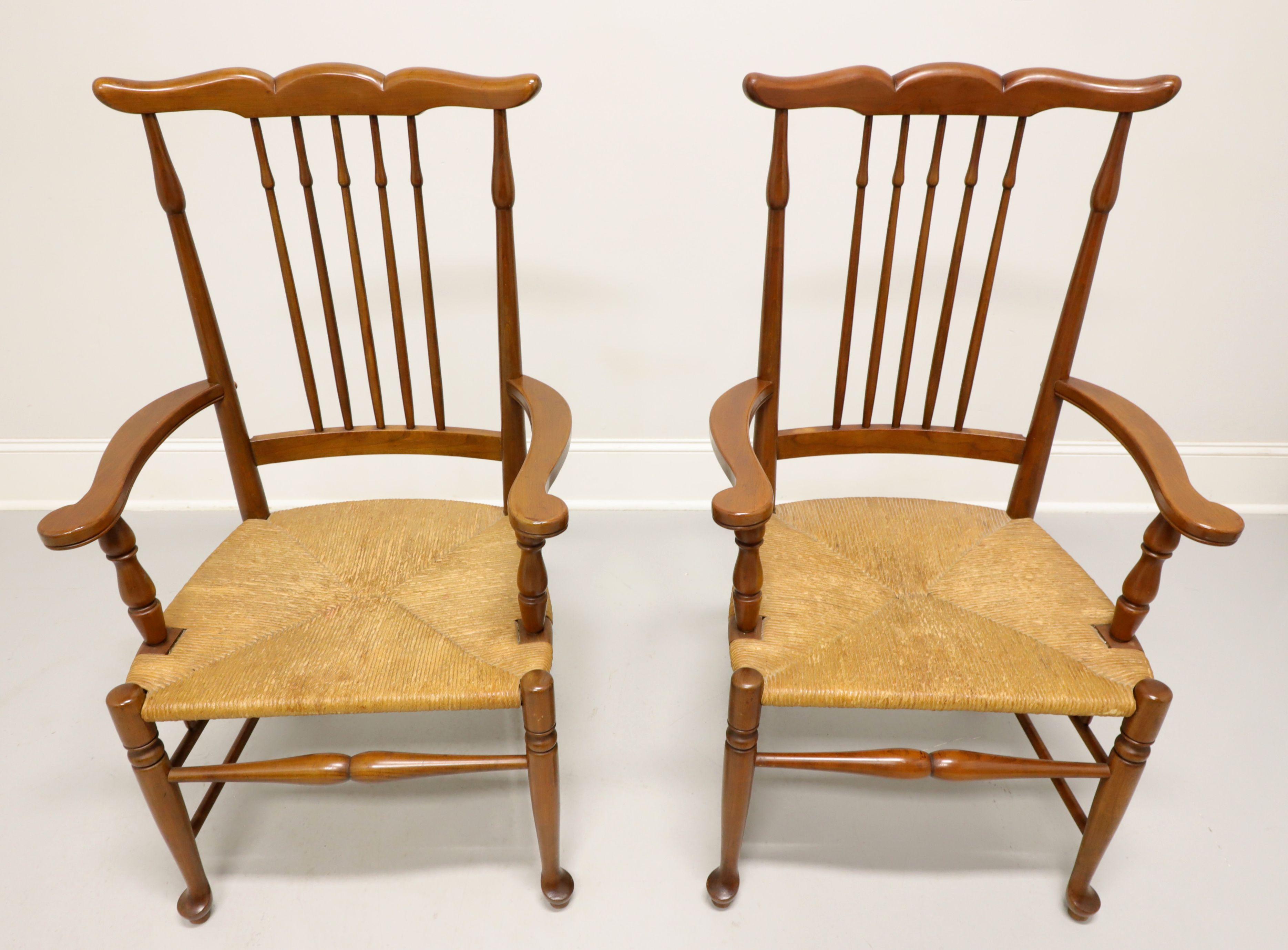 A pair of dining armchairs in the Rustic Farmhouse style, unbranded, similar in quality to Ethan Allen. Solid cherry, uniquely carved crestrail, spear shaped stiles & backrest spindles, slightly curved flat arms with turned supports, rush seats,