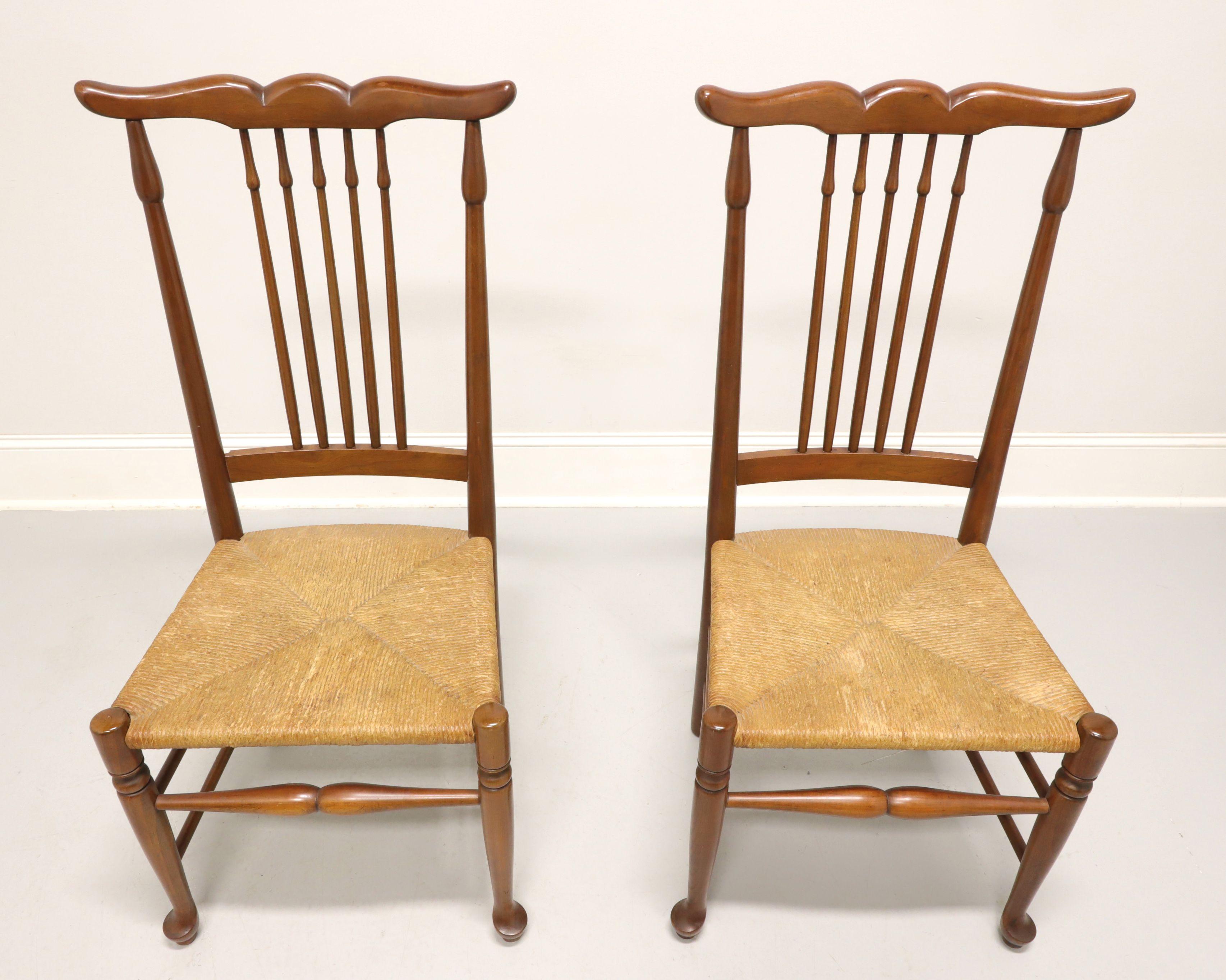 A pair of dining side chairs in the Rustic Farmhouse style, unbranded, similar in quality to Ethan Allen. Solid cherry, uniquely carved crestrail, spear shaped stiles & backrest spindles, rush seats, turned front stretcher, turned front legs and pad
