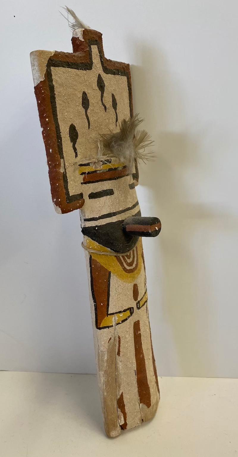 This is an excellent replica of a 19th century child's kachina Doll with a flat, wood tableta headdress and concave back. It is made of cotton wood and hand painted with a textured paint. With distressed feathers, old string, and a chipped paint