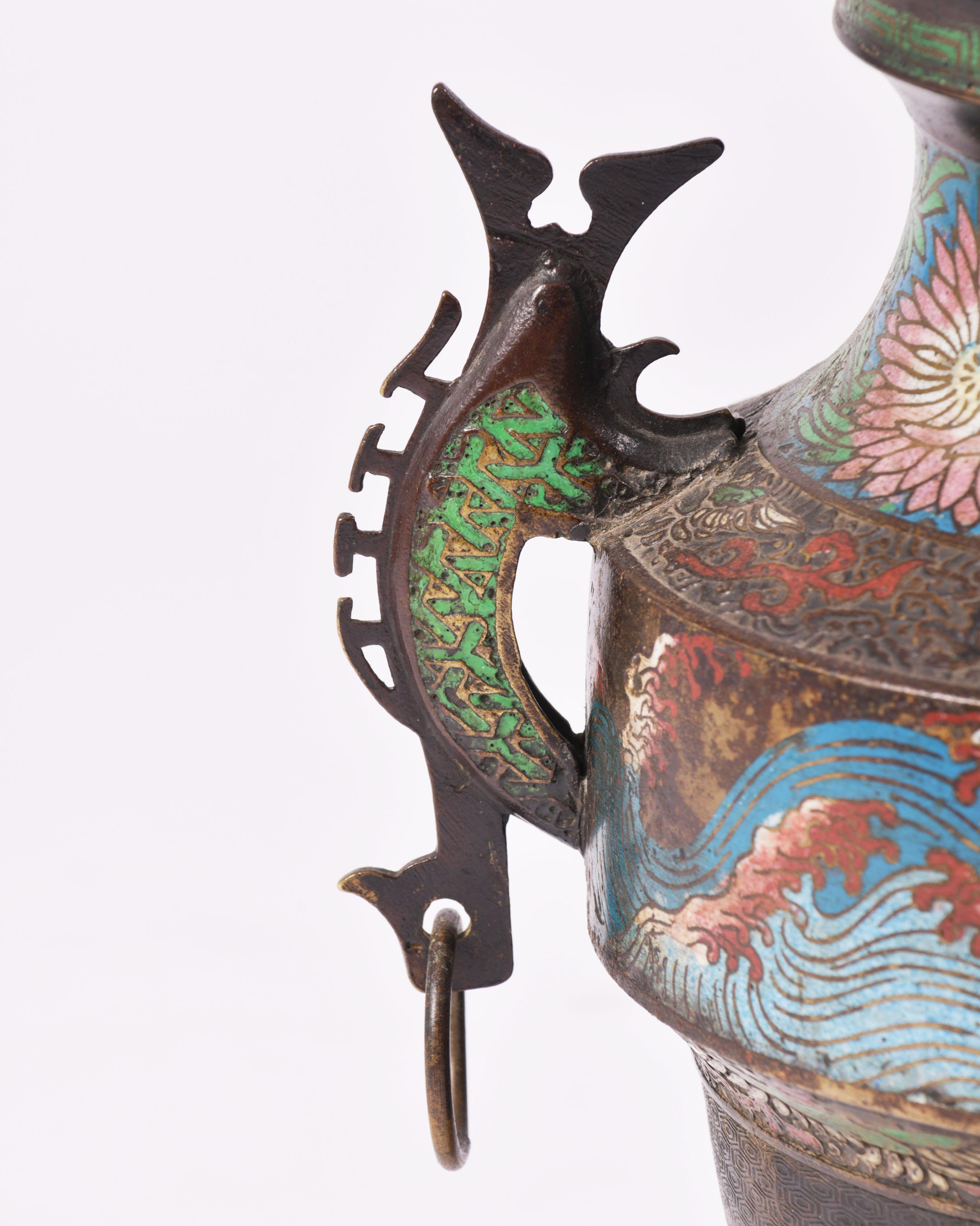 This very striking mid-20th century Japanese enameled bronze censer features an ornately enamel painted design of stylized flowers and mountain scenes. It has attractive cut work in both the base and the top, with a foo dog finial. This enameled