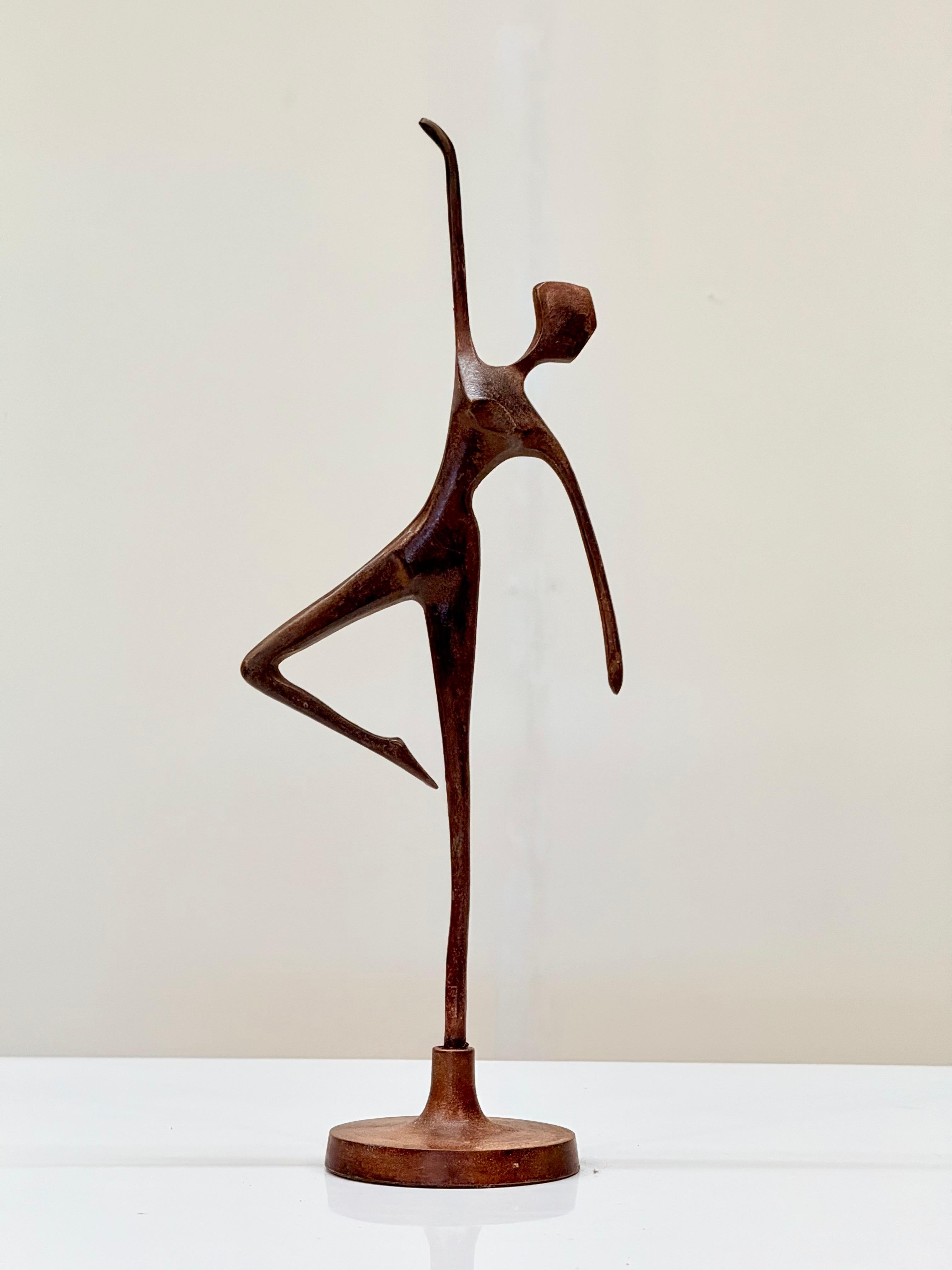 A mid-20th century Chinese bronze figurine depicting a stylized dancer in a dynamic pose, with one leg raised and arms gracefully extended, capturing the fluidity of movement. The abstract form features elongated limbs, a simplified torso, and a
