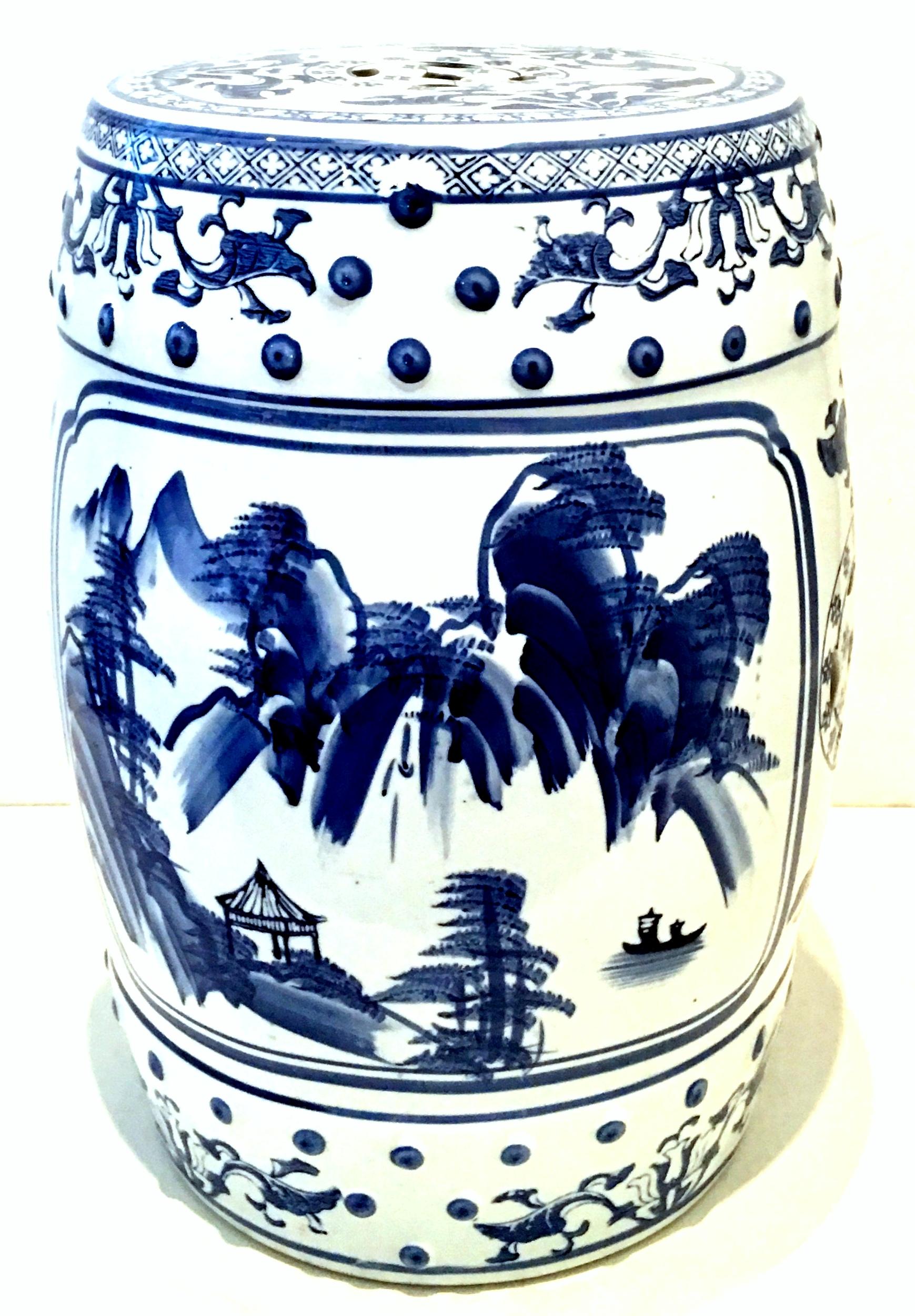 Mid-20th century Chinese export hand-painted porcelain blue and white garden stool. This lovely piece has a mountain lake house motif on one side and floral motif on the opposite side. Features raised dot detail and Chinese geometric cut-out symbols