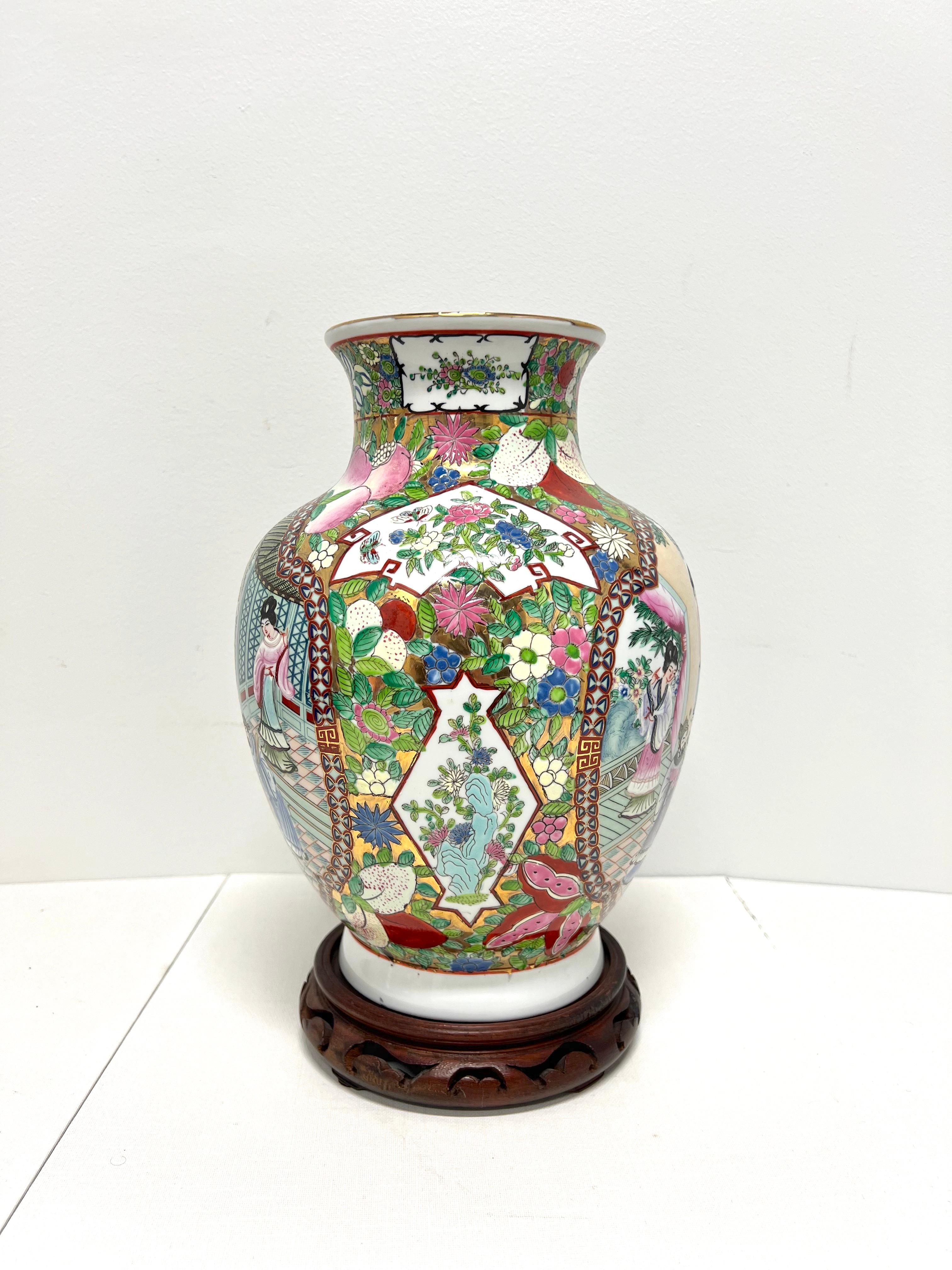 A Mid 20th Century Chinese Export style decorative porcelain vase with stand, unbranded. A beautiful multi-color porcelain broad urn shaped vase with hand painted Chinoiserie scenes, a textured finish, and a separate decoratively carved round wood
