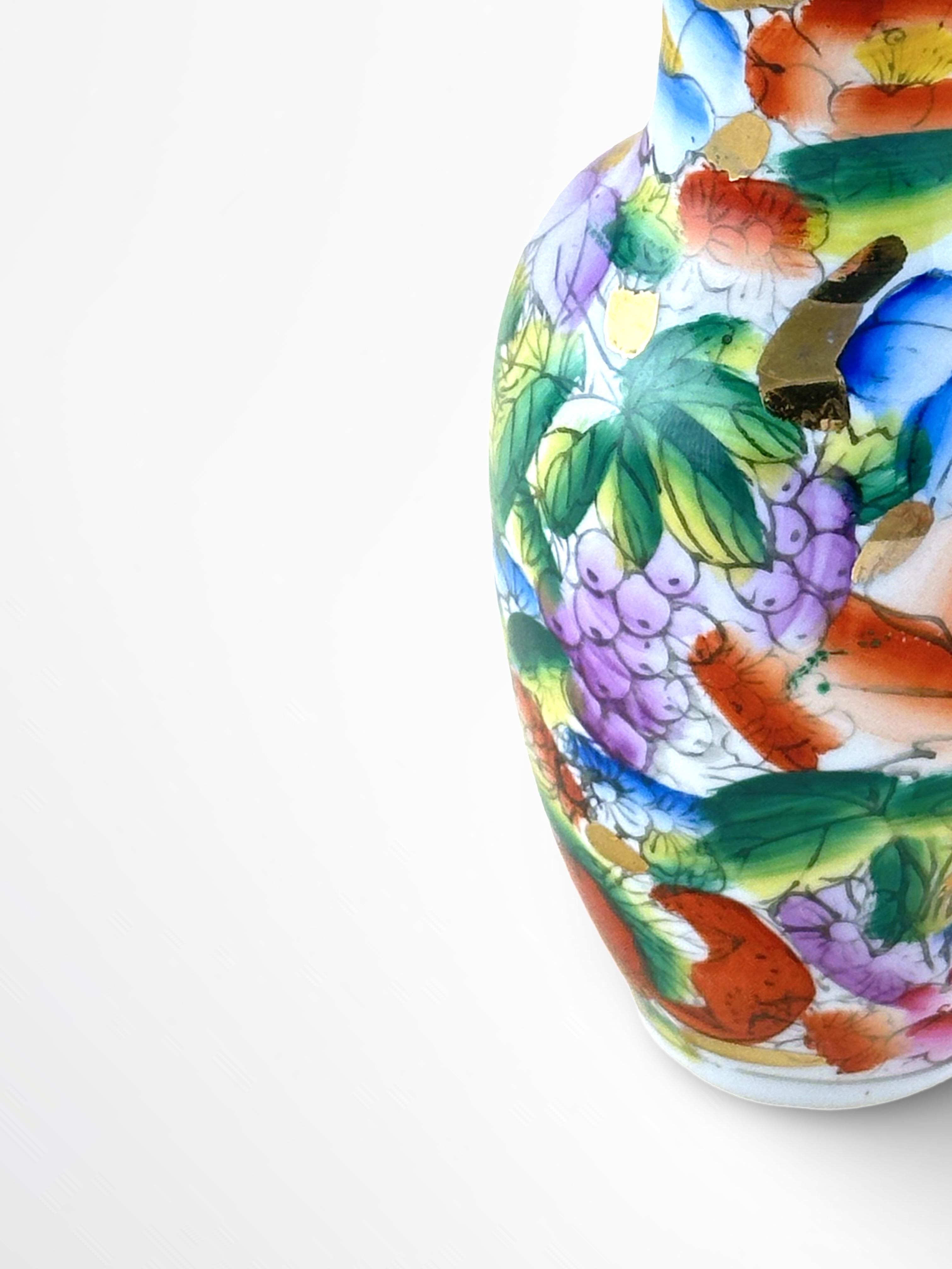 A small porcelain baluster vase, handcrafted in China during the mid-20th century, specifically between the 1950s and 1960s

Finely decorated and displaying a vibrant scene of flowers nestled against a contrasting bed of lush green foliage. Bright