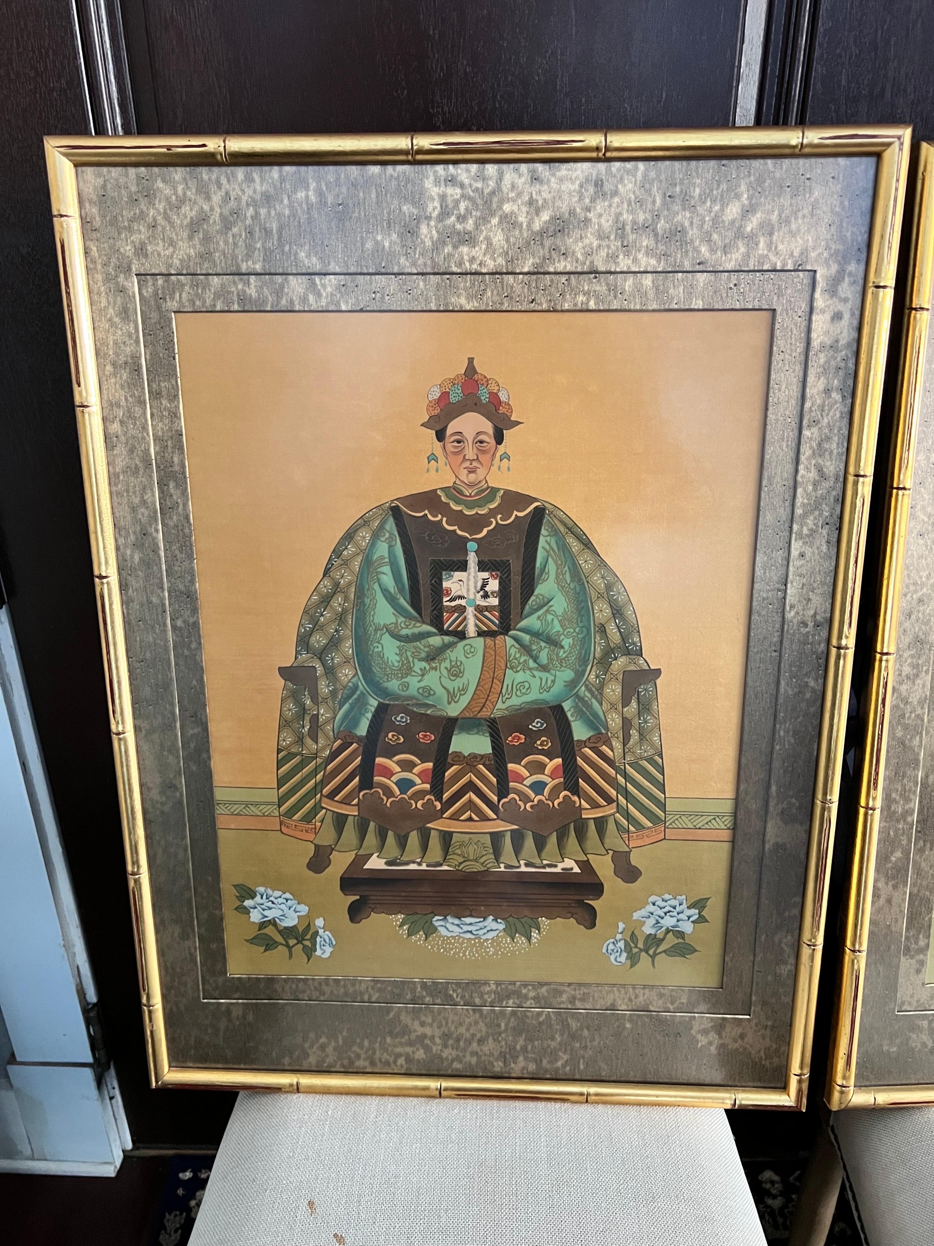 Stunning pair of vintage hand painted watercolor on silk portraits depicting a Chinese Emperor and Empress. They are wearing highly detailed robes in shades of aqua and terra cotta. Each is beautifully framed in a gold faux bamboo wood frame, and