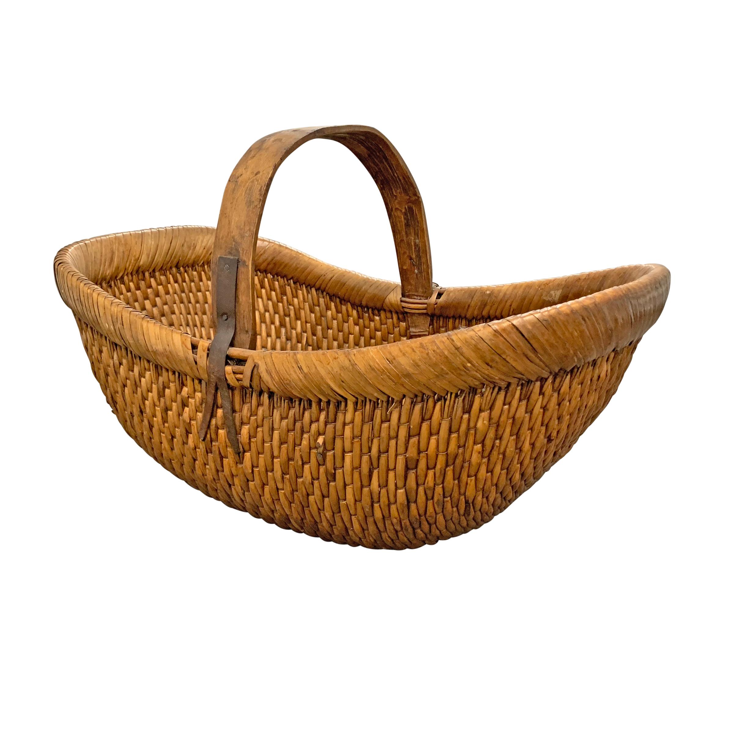 A mid-20th century Chinese woven reed gathering basket with a bentwood handle attached with simple iron straps.