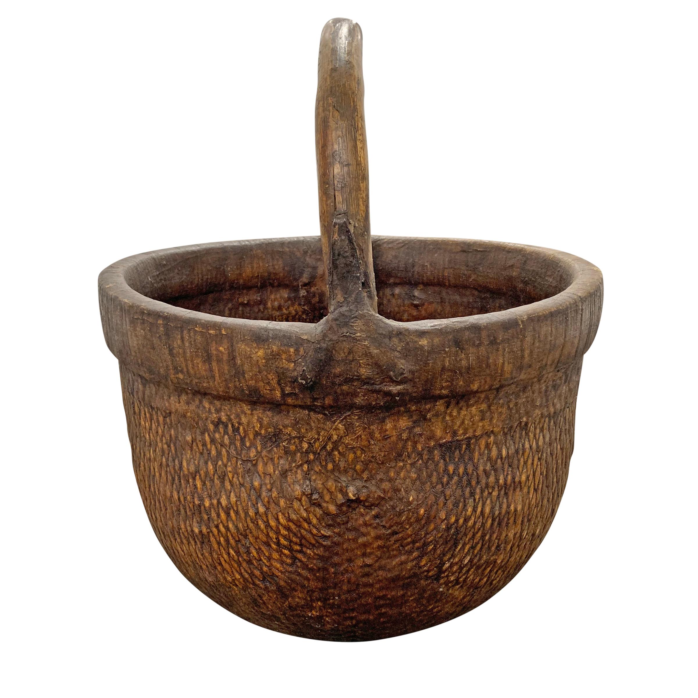 Un panier de collecte en roseau tressé chinois du milieu du 20e siècle avec une épaisse poignée en bois courbé attachée avec de simples sangles en fer, et recouvert de tissu laqué pour plus de solidité.