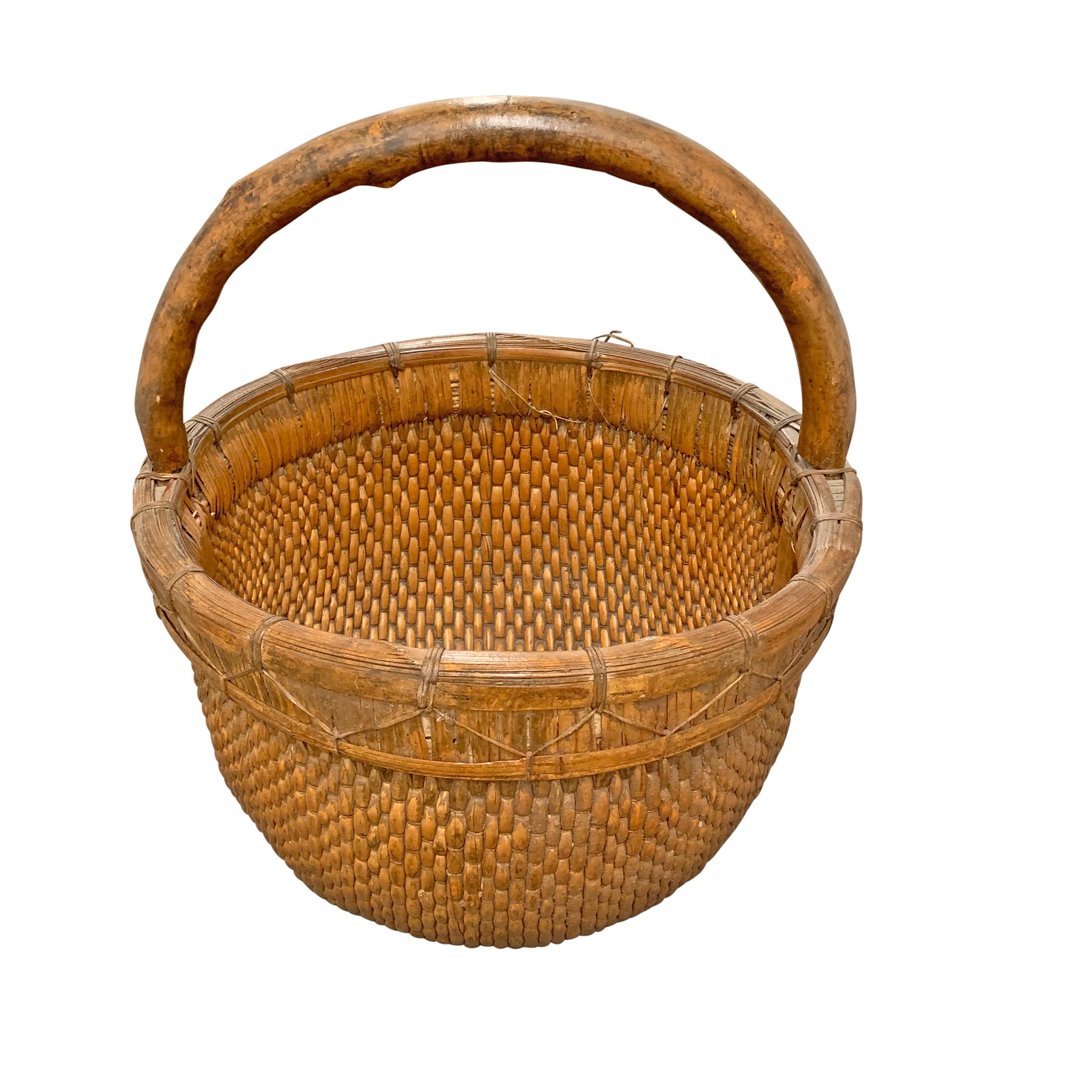 Un panier de collecte en roseau tressé chinois du milieu du 20e siècle avec une épaisse poignée en bois courbé attachée à une épaisse bande lourde avec un laçage en roseau tressé.