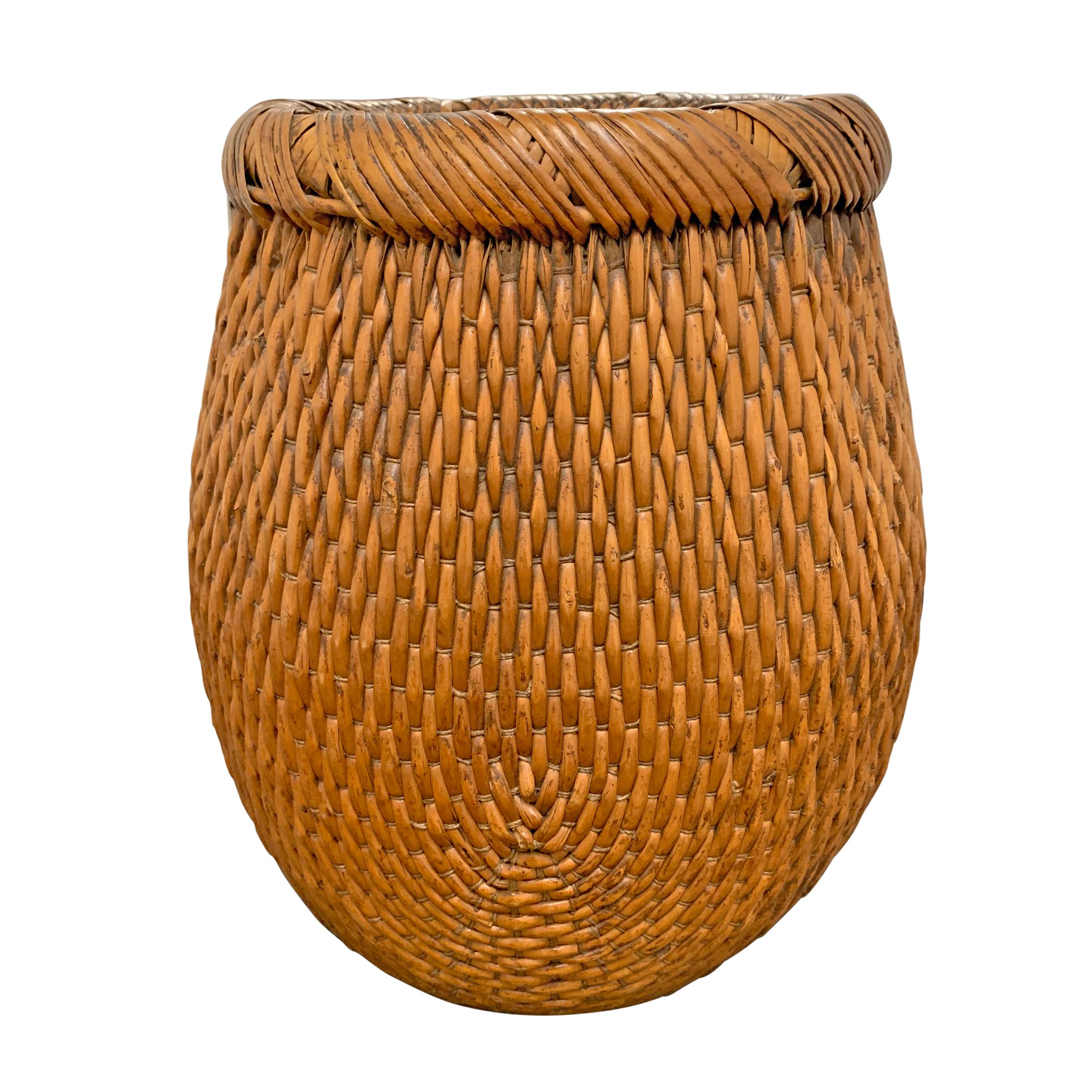 A mid-20th century Chinese woven reed basket with a rolled banded top wrapped in flat reeds.