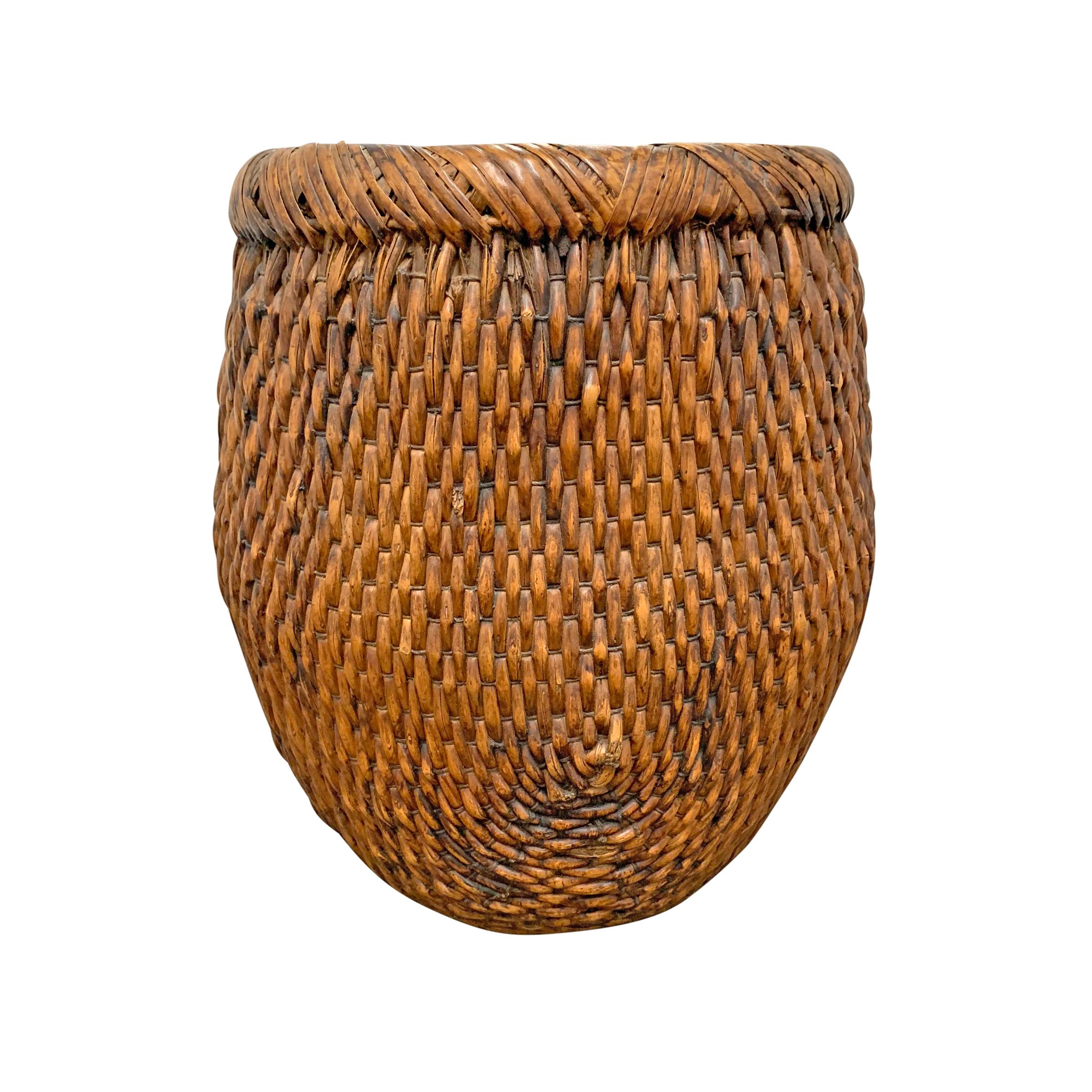 A mid-20th century Chinese woven reed basket with a rolled banded top wrapped in flat reeds.
