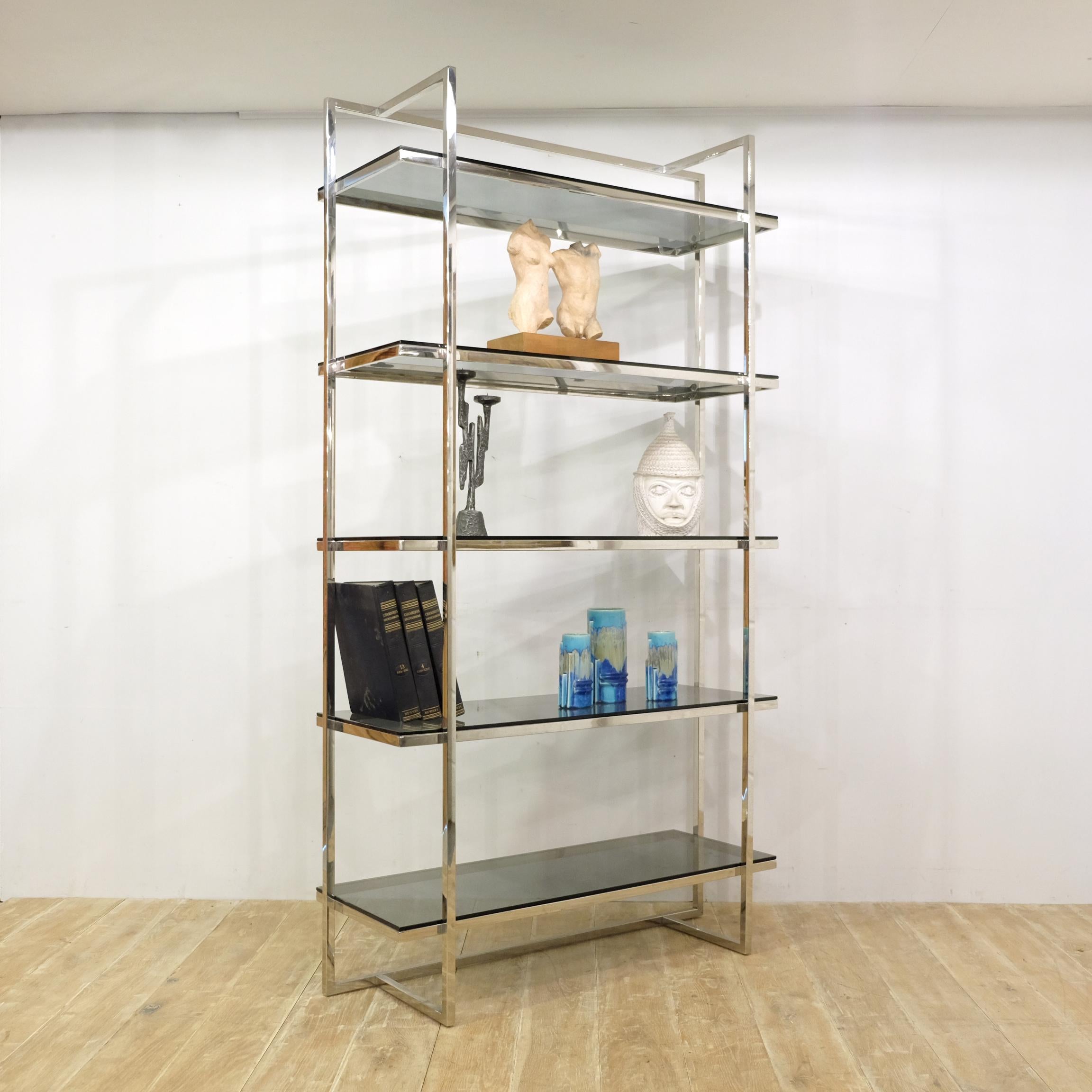 A mid-late 20th century freestanding shelving unit in chromed metal with five thick smoked glass removable shelves. A stylish piece with a somewhat modernist feel, though this one is likely 1970s. Simple, angular, sleek and unusual design. Similar