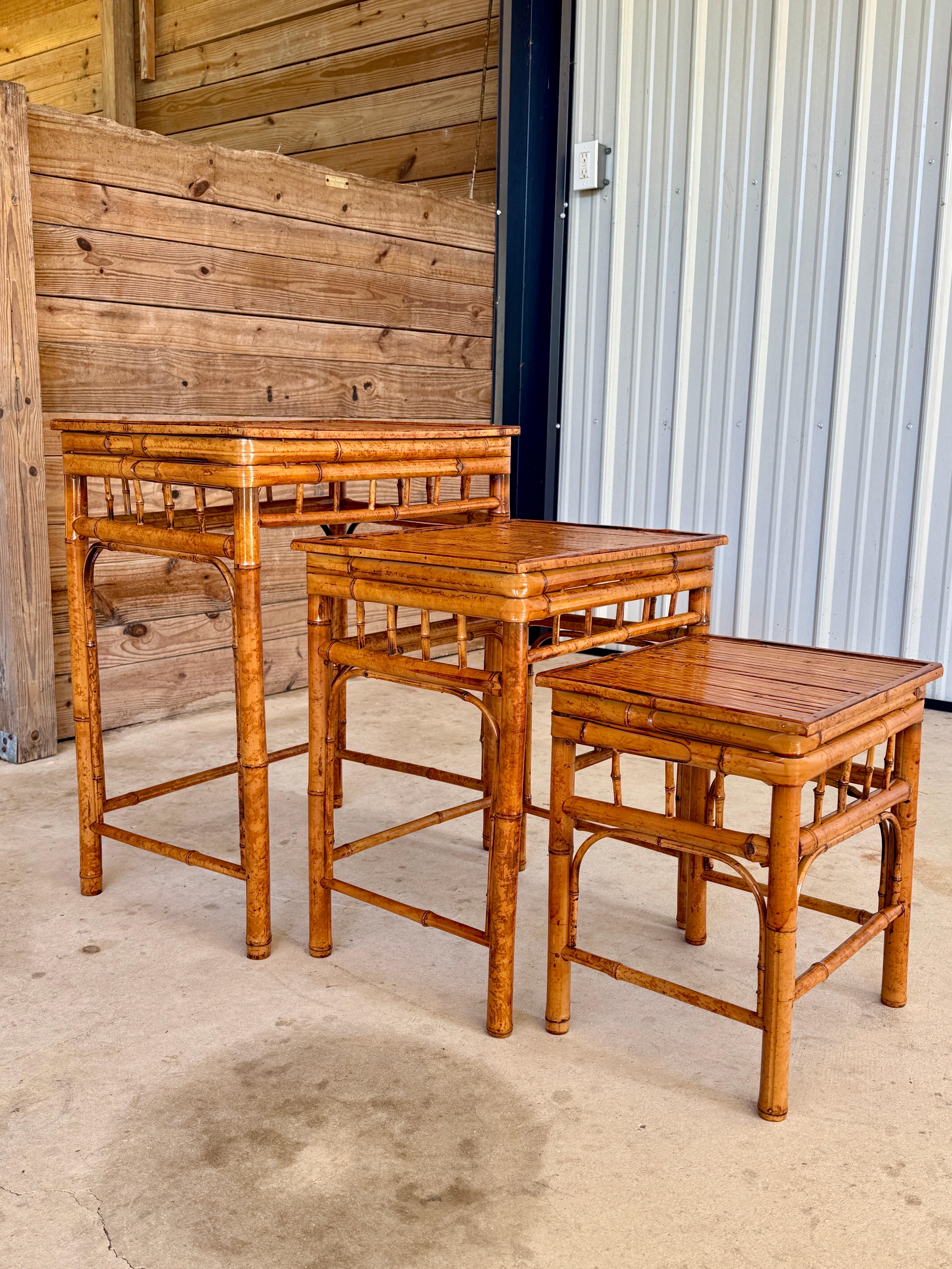  Trio classique de style Coastal Regency du milieu du siècle, cet ensemble de tables empilables en bambou brûlé apporte chaleur, texture et ces tons mouchetés emblématiques de l'Icone. Entièrement rénové avec un éclat frais et brillant, tout en